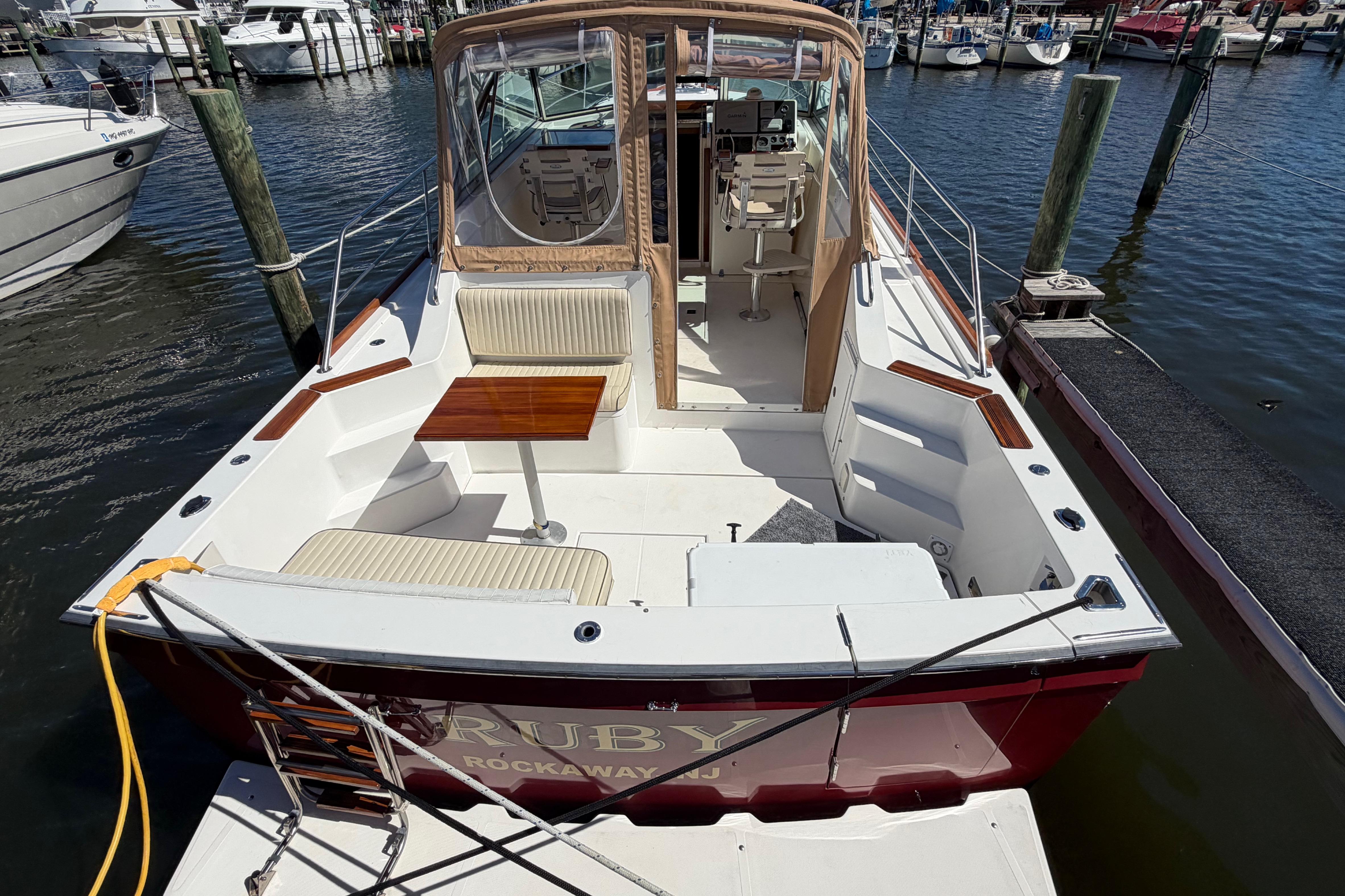 2000 Sabreline 36 Express boat docked at marina, featuring spacious seating and table.