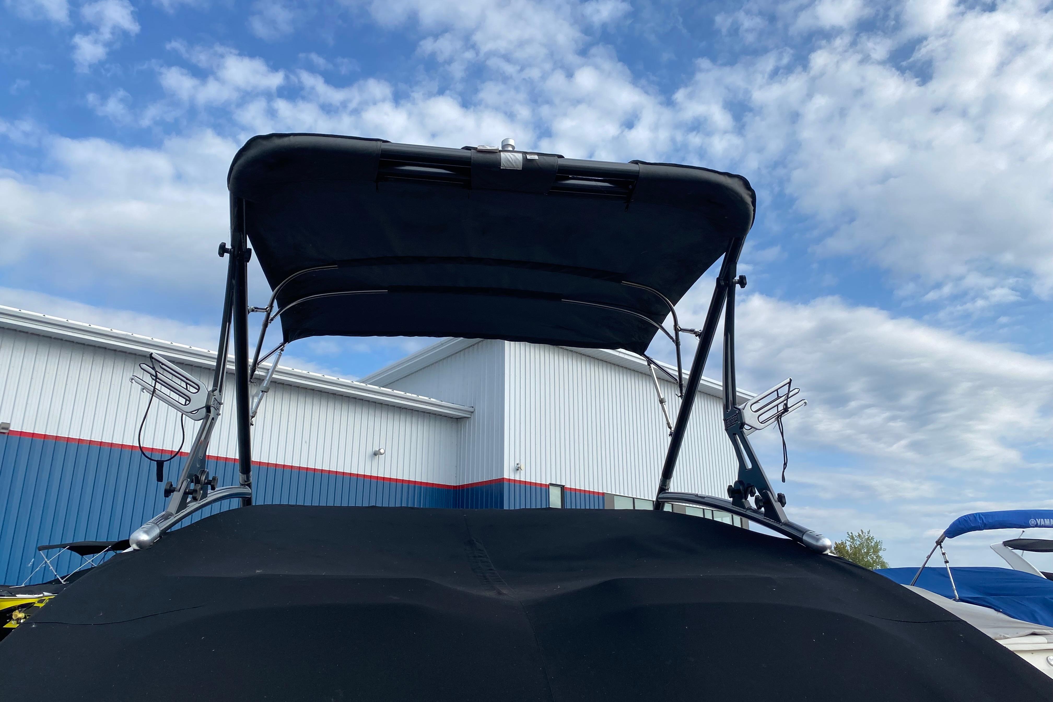 2015 Yamaha Boats 212X with bimini top, docked under a partly cloudy sky.