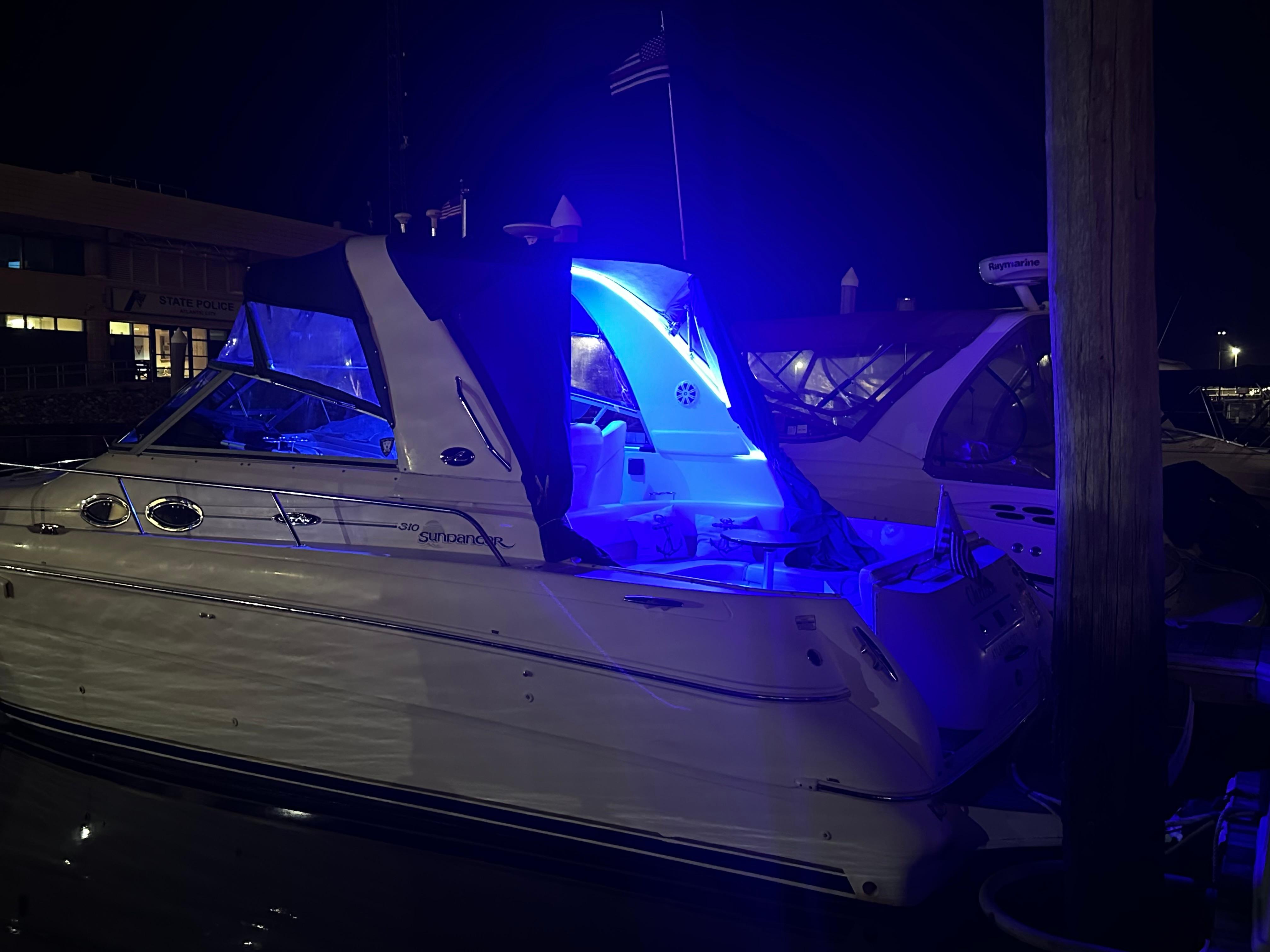 2002 Sea Ray 310 Sundancer yacht illuminated with blue lights at night.