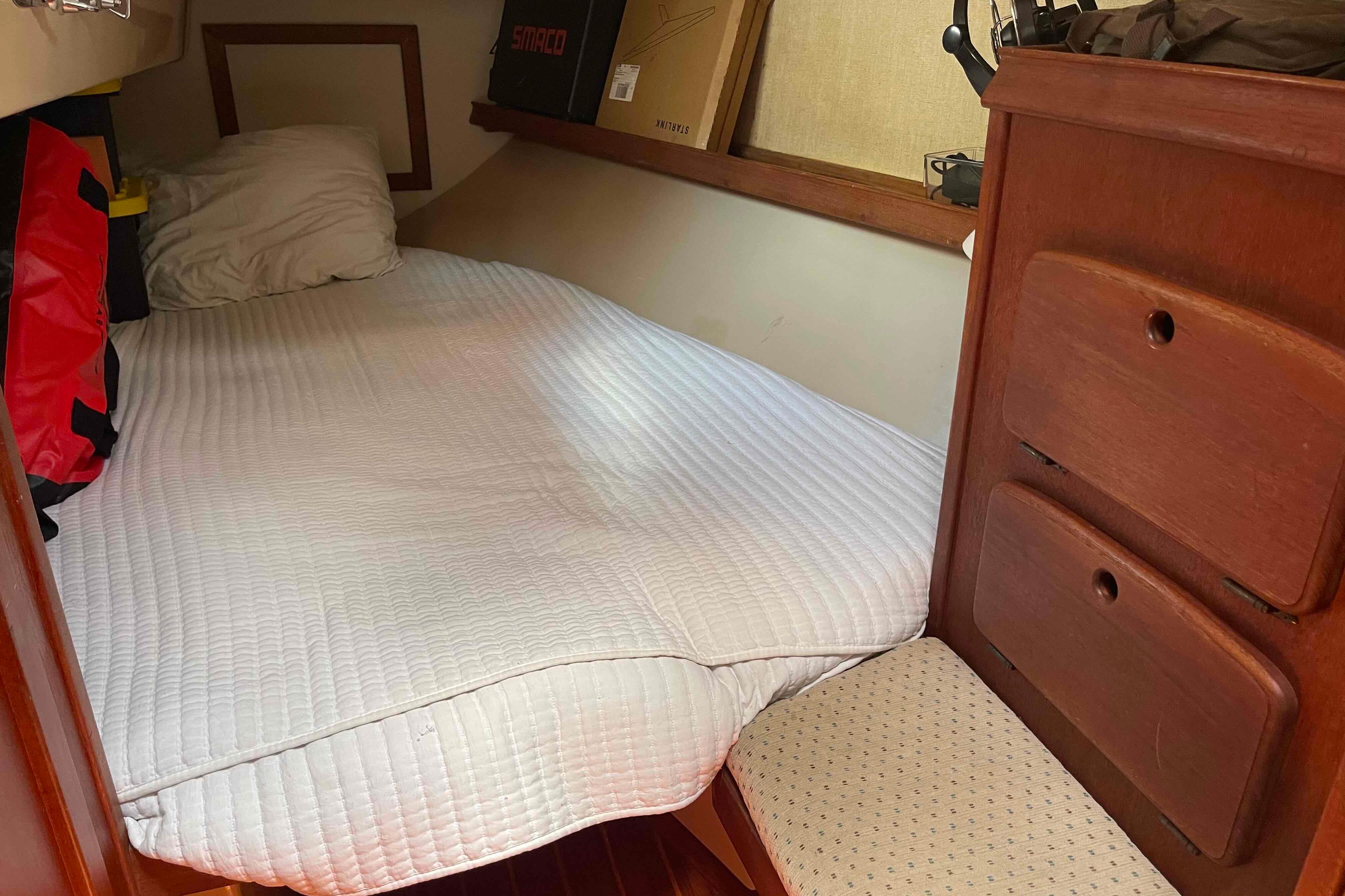 Cozy cabin interior of 1989 Island Packet 35 sailboat with bed and wooden storage.