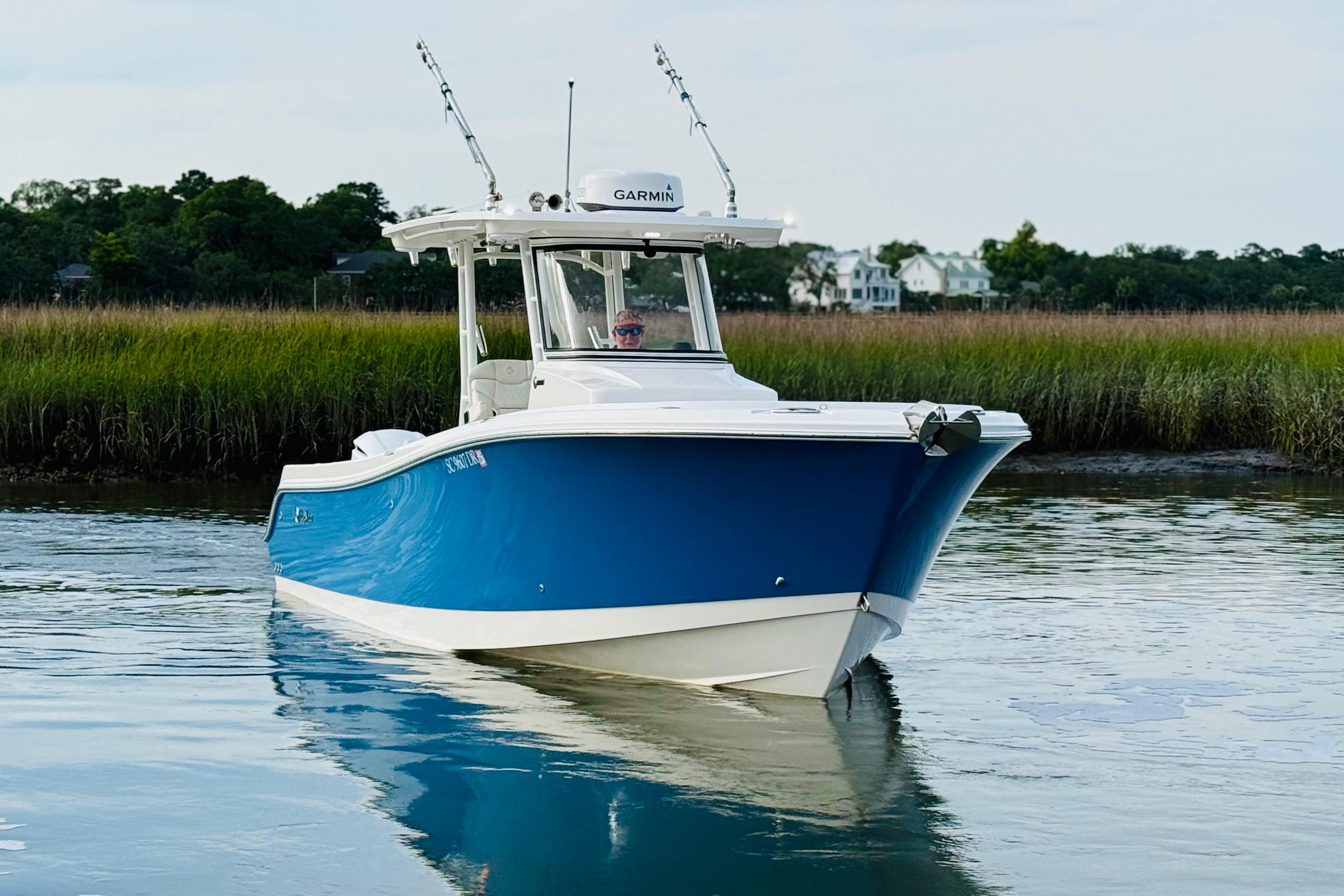 2022 Edgewater 280CC boat cruising on calm water near grassy shoreline.