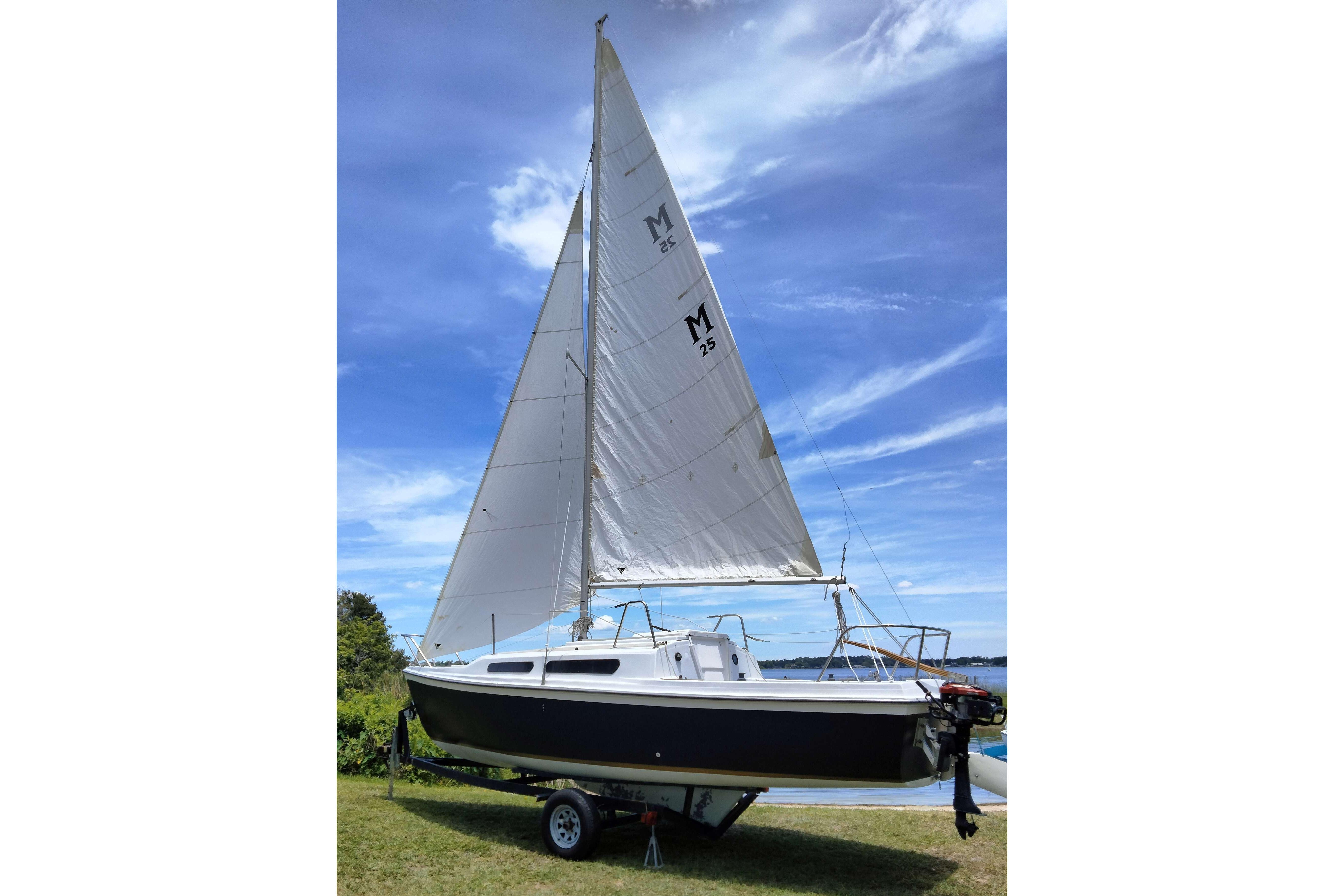 1980 MacGregor 25 sailboat on trailer, set against a clear blue sky.