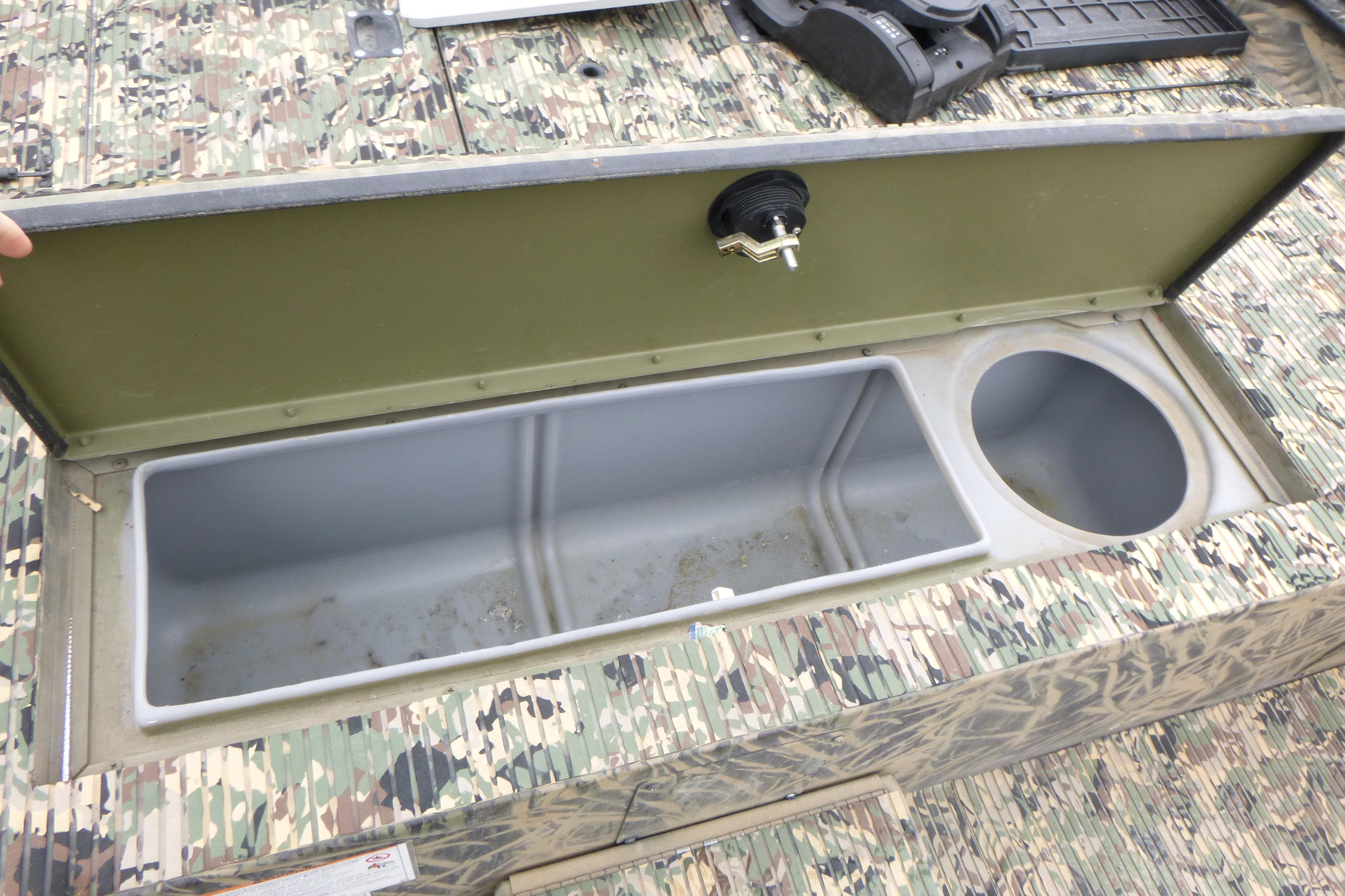 Open storage compartment on 2024 Lowe Roughneck 2070 boat with camouflage design.