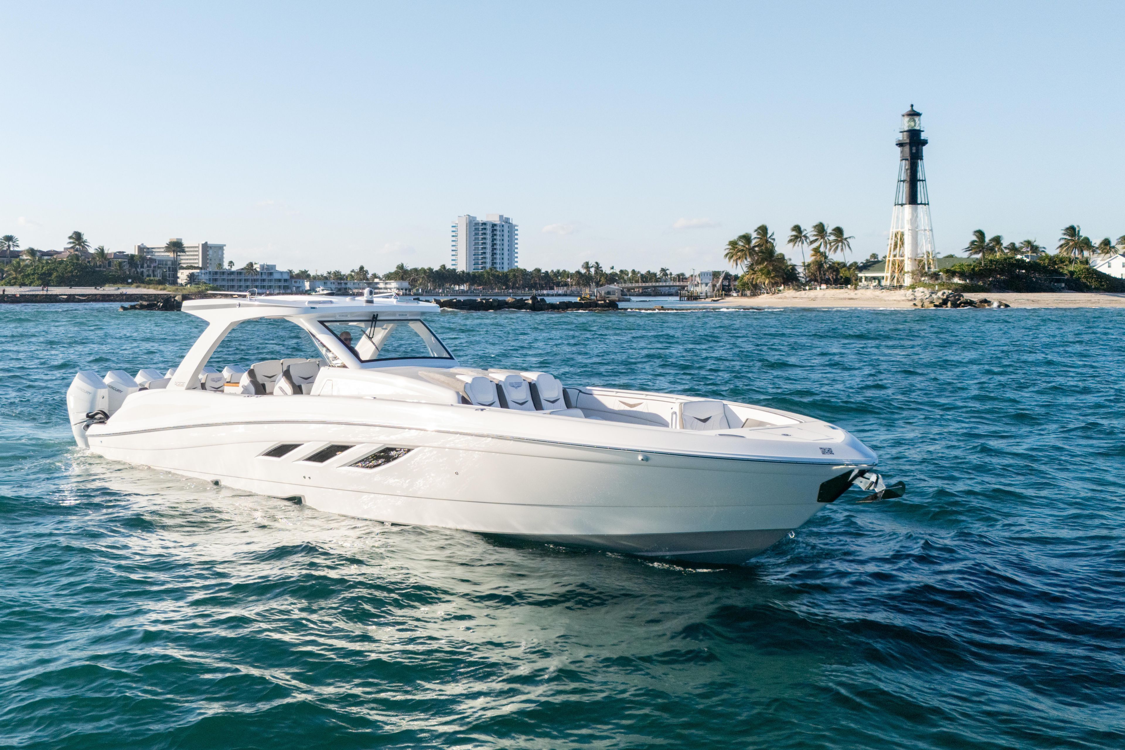 Luxury 2026 Deep Impact 499 Sport boat cruising near a scenic lighthouse.