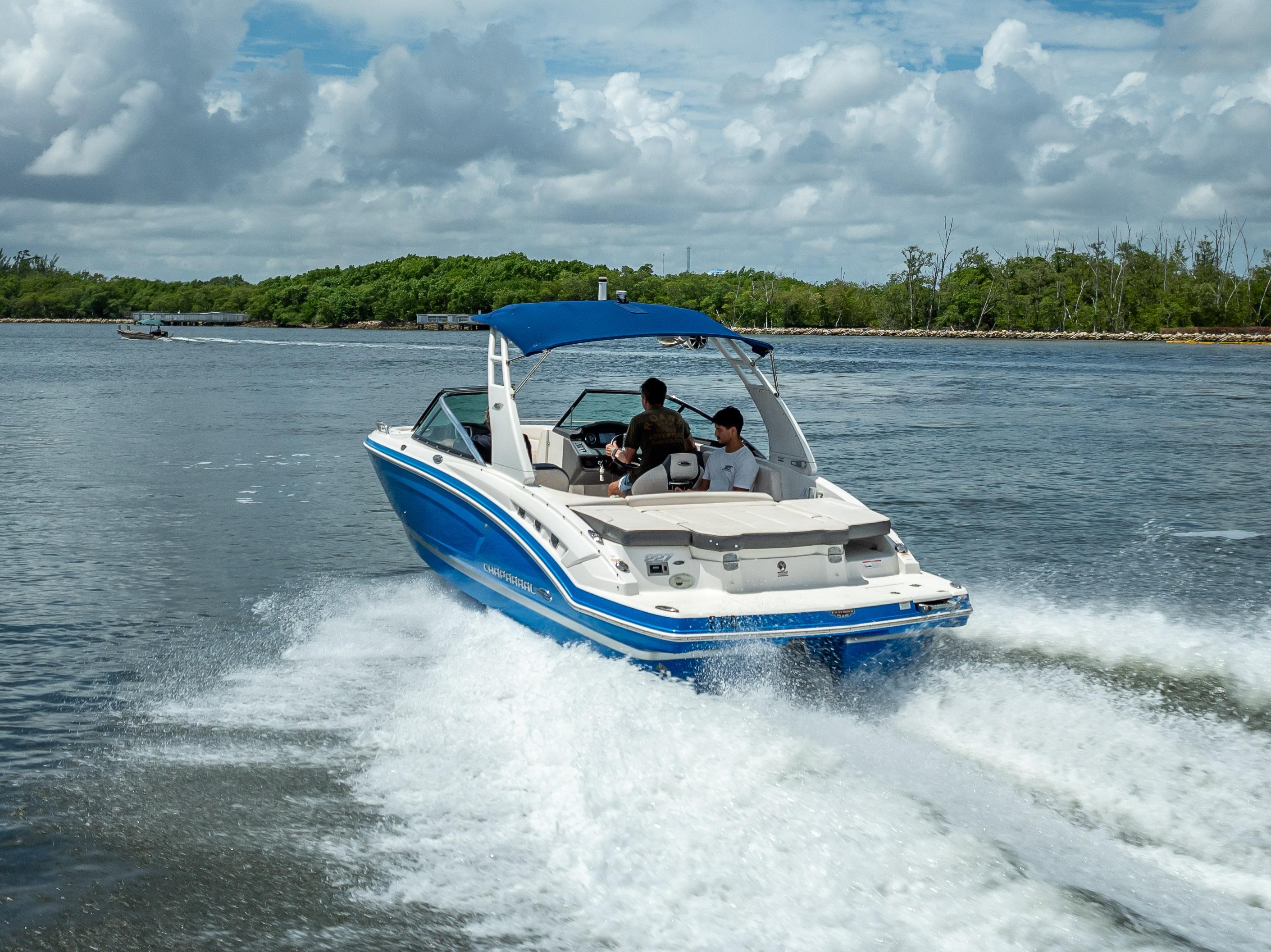 2017 Chaparral 227 SSX boat cruising on a scenic waterway under a cloudy sky.