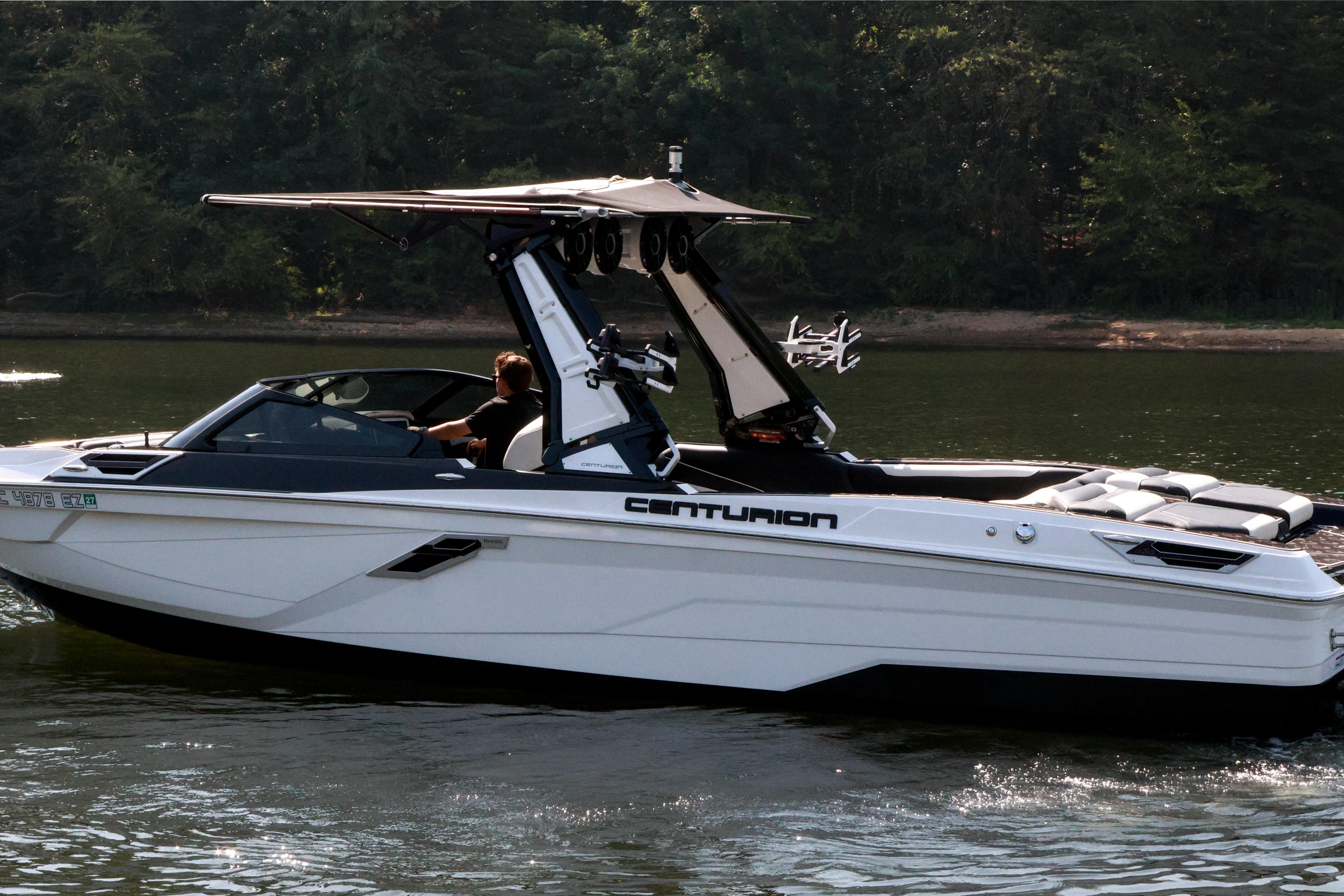2022 Centurion Ri265 boat cruising on a calm lake with lush forest background.