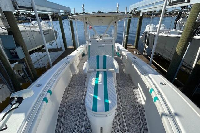 2002 Yellowfin 31 Center Console boat with teal accents docked by the water.