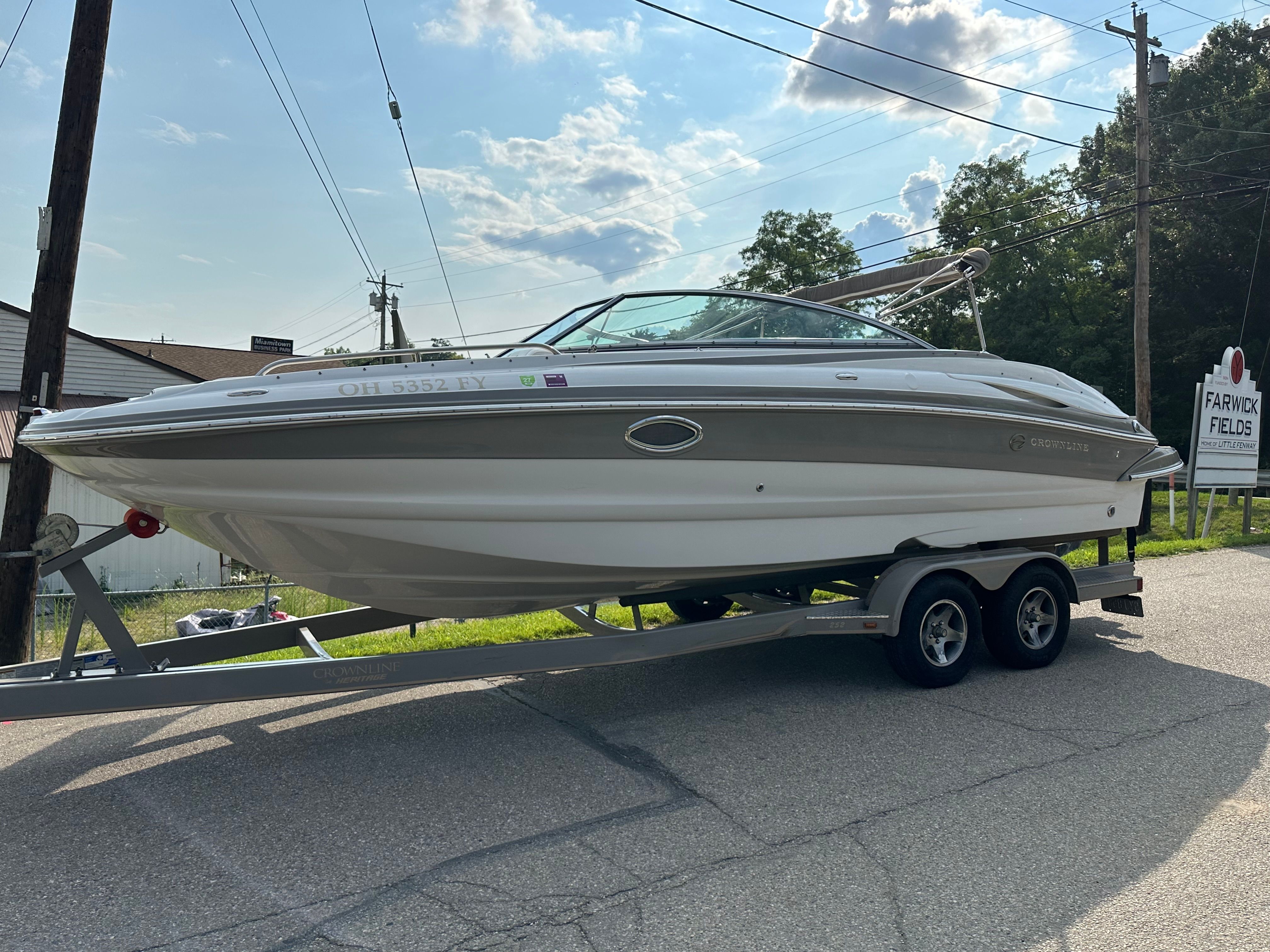 A 2007 Crownline 252 EX boat on a trailer, parked on a street.