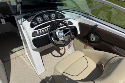 2017 Rinker QX21 BR boat cockpit with steering wheel and beige seating.