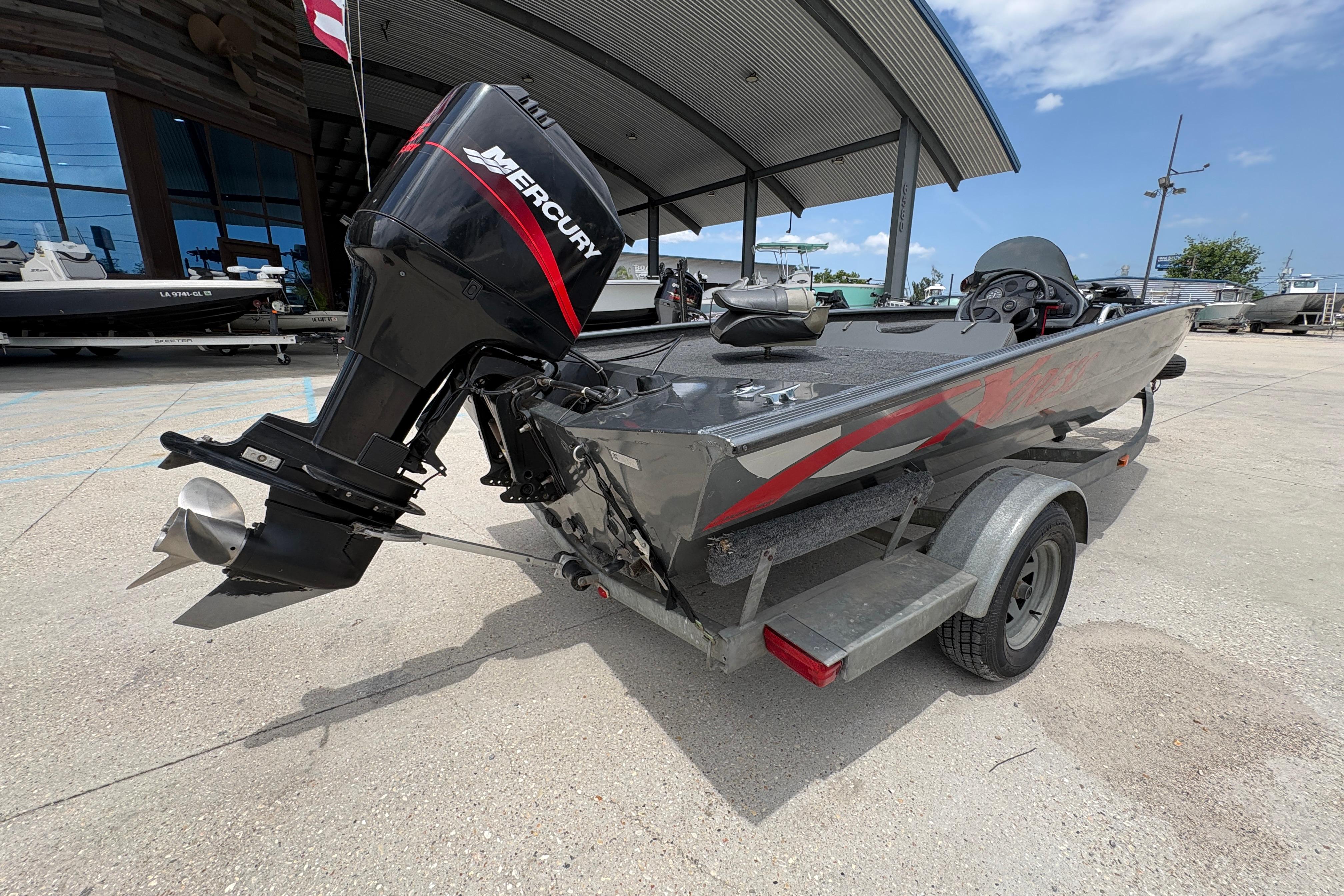 2000 Xpress X18 boat with Mercury outboard motor on trailer, parked outdoors.