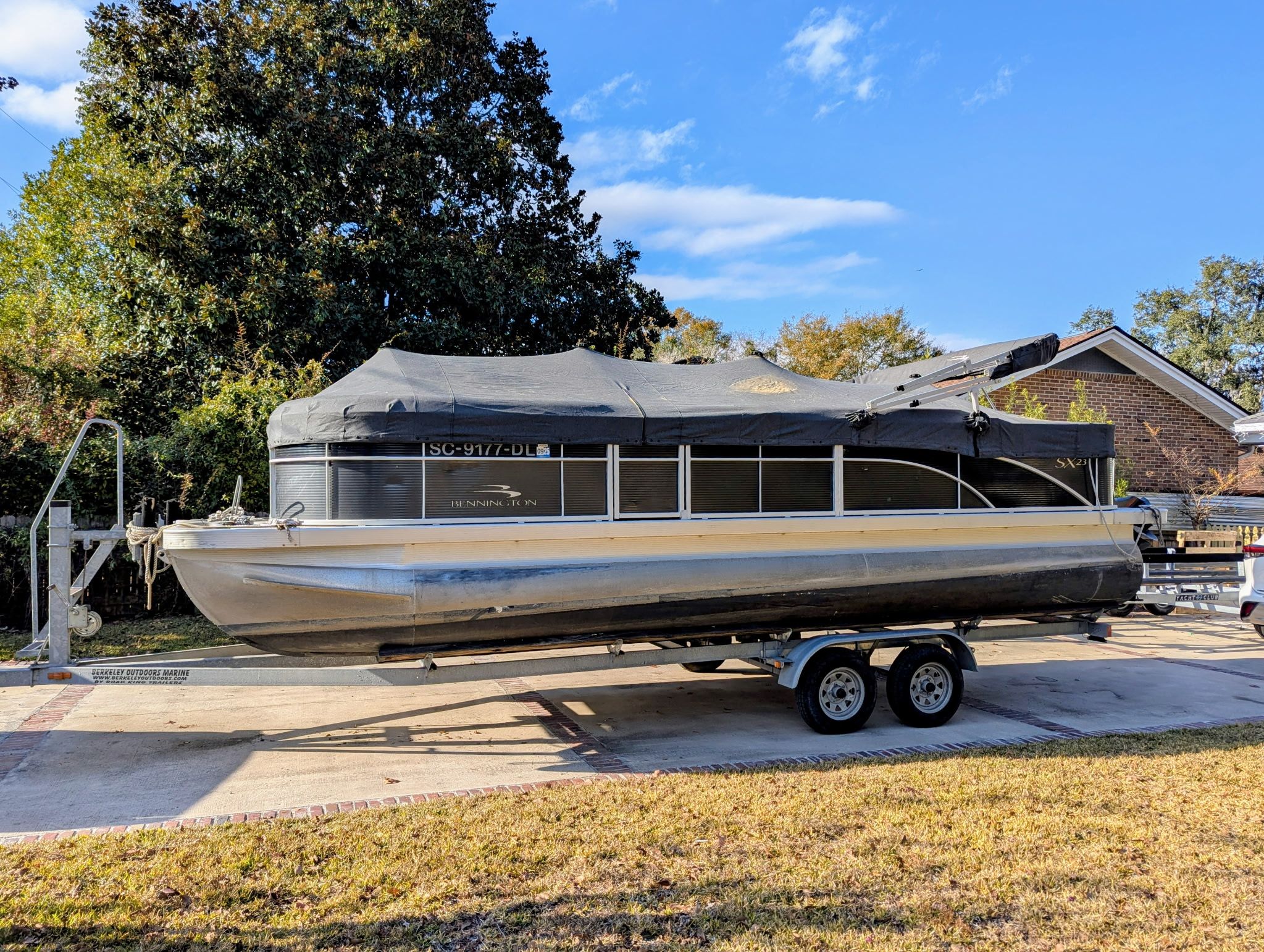 A 2019 Bennington 23 SX pontoon boat on a trailer in a driveway.