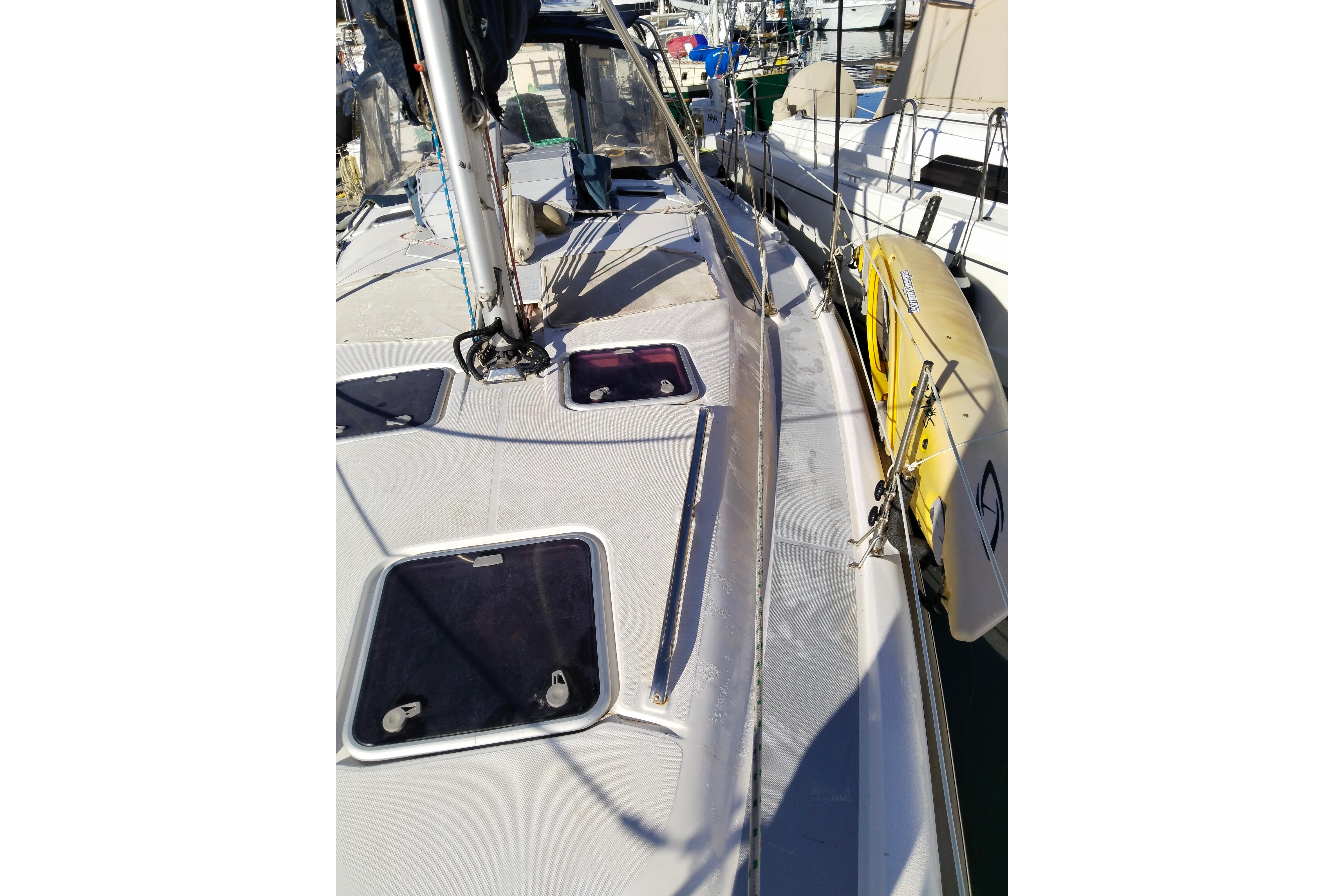 1999 Hunter 380 sailboat deck with hatches and docked yellow dinghy.