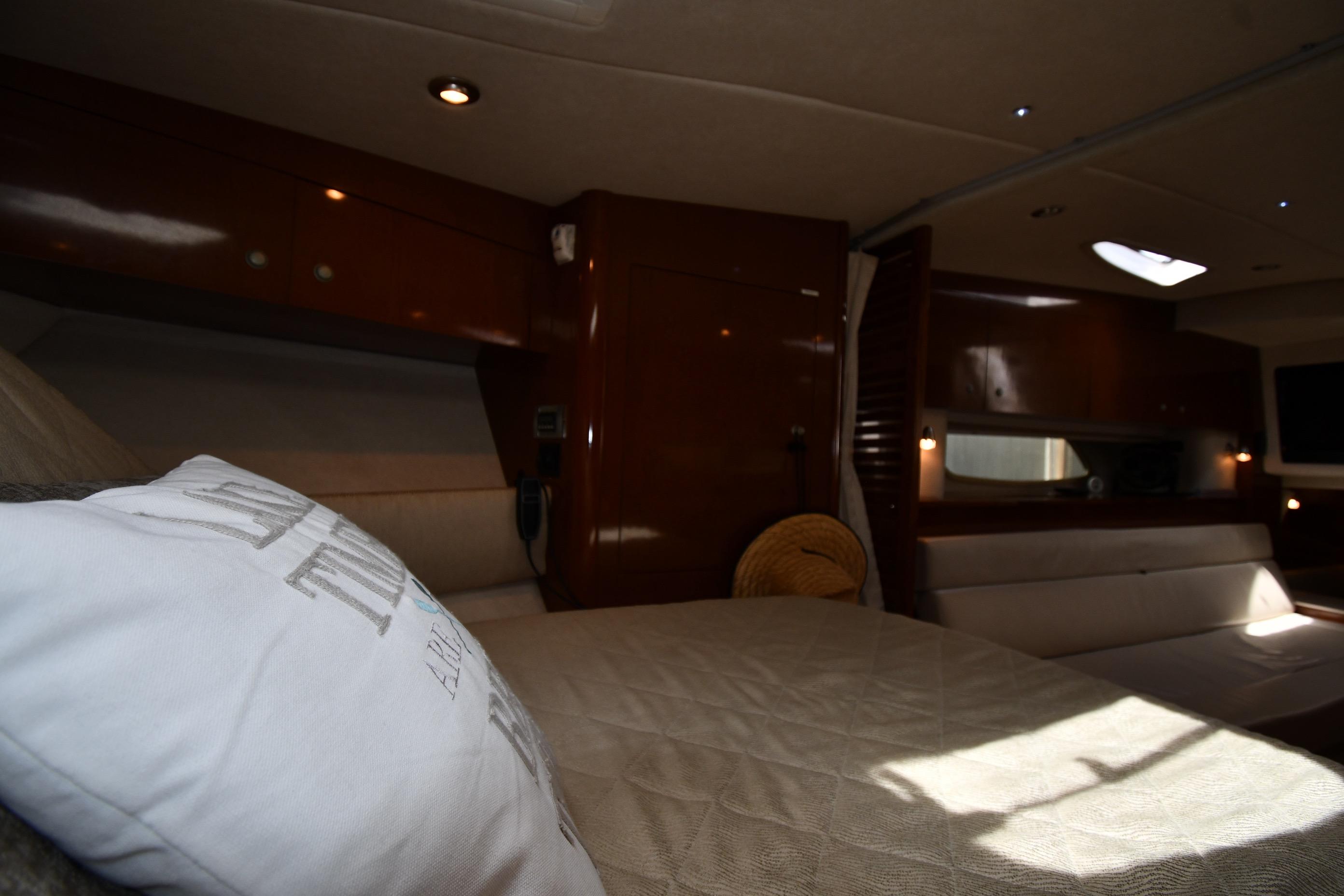 Interior cabin of 2008 Sea Ray Sundancer 350 yacht, featuring cozy bedding and elegant wood finishes.