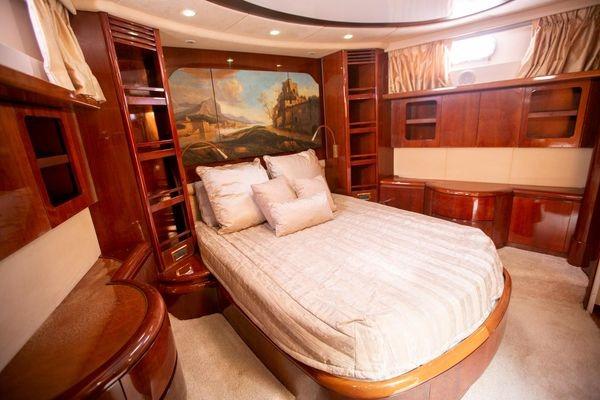 Luxurious bedroom interior of 2003 Azimut 74 Solar yacht with elegant wood finishes.