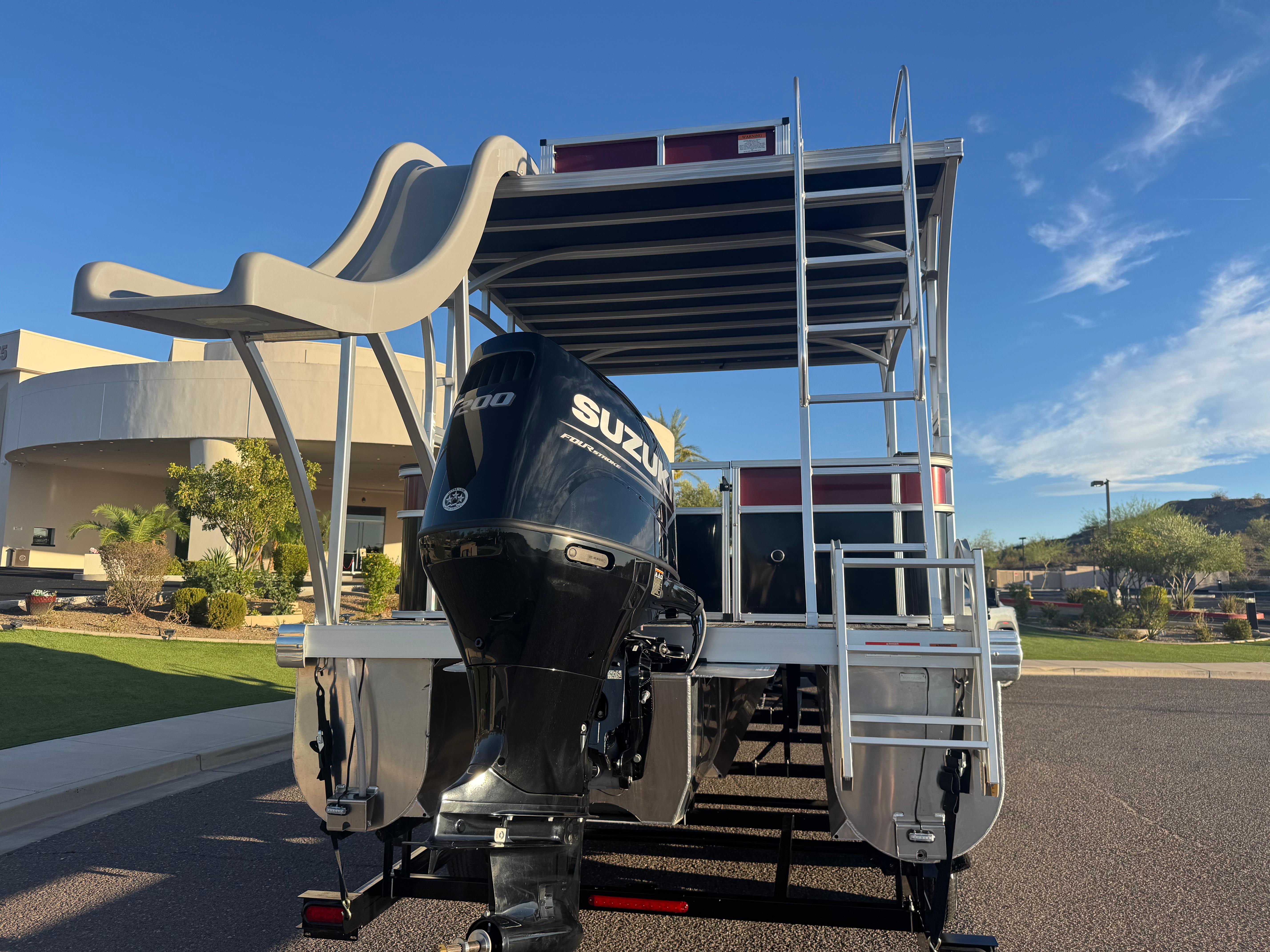 2024 Landau Island Breeze 252 pontoon boat with Suzuki engine and slide, parked outdoors.