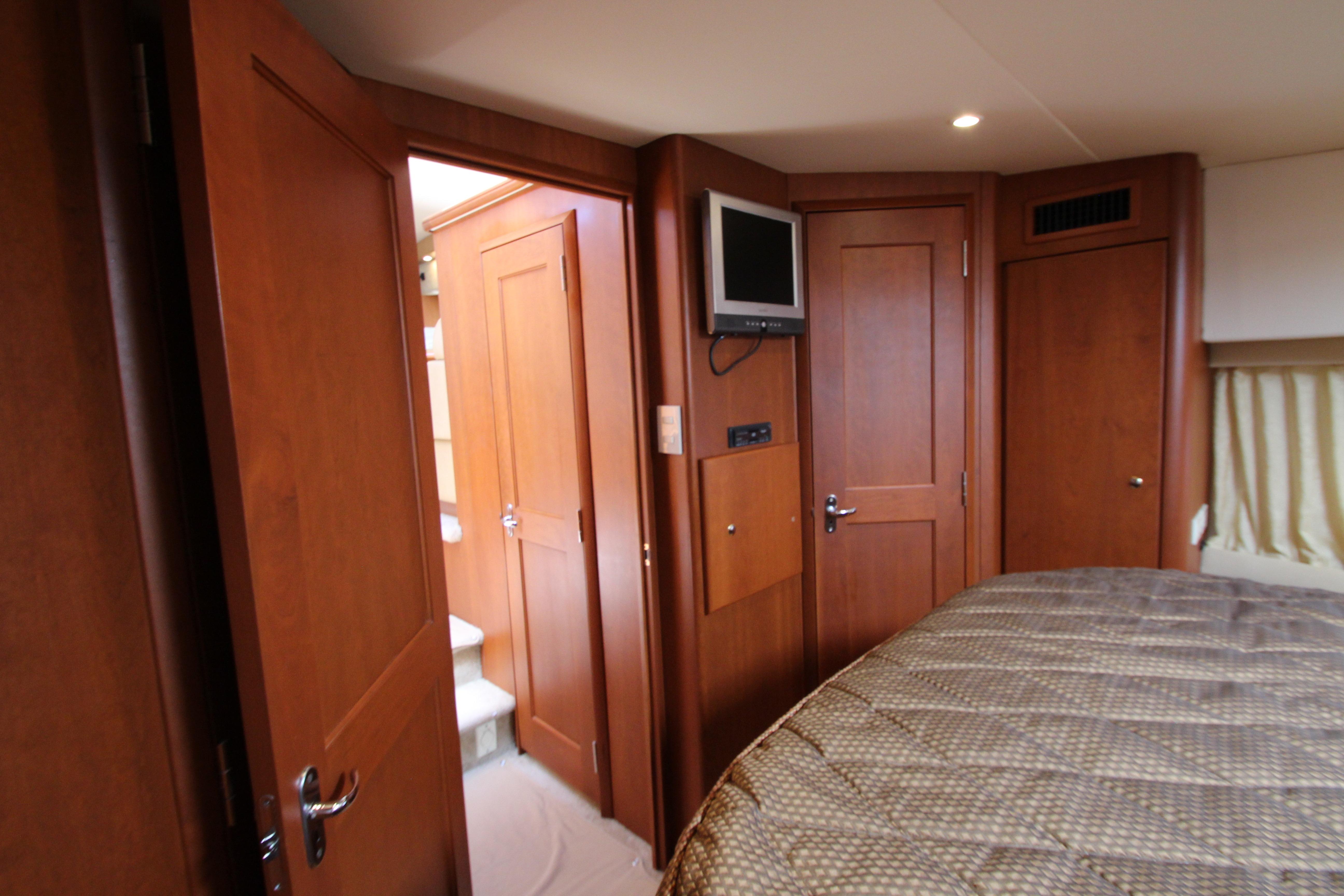 Interior of 2006 Silverton 38 Sport Bridge yacht with wood paneling and cozy bedroom.