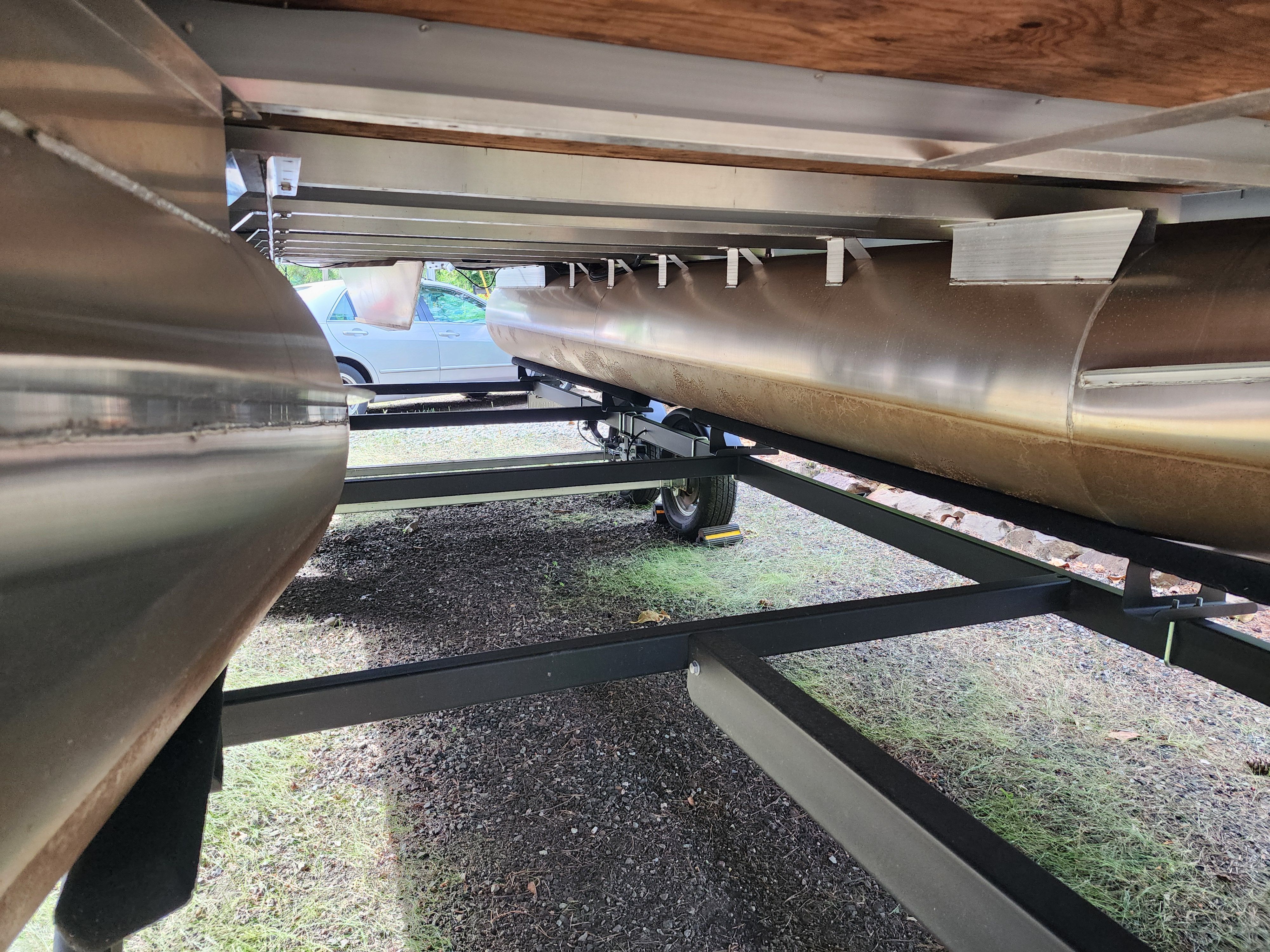 Underside of a Bennington 22 LSB pontoon boat on a trailer, featuring metal framework and wheels.