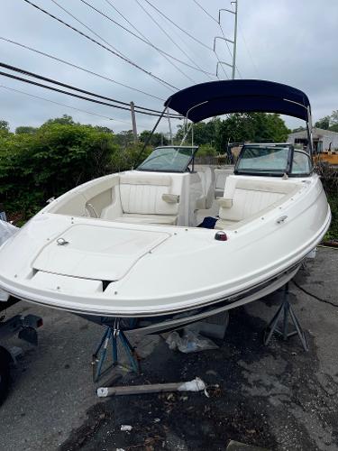 2013 Sea Ray 240 Sundeck boat with canopy, parked on stands, overcast sky.