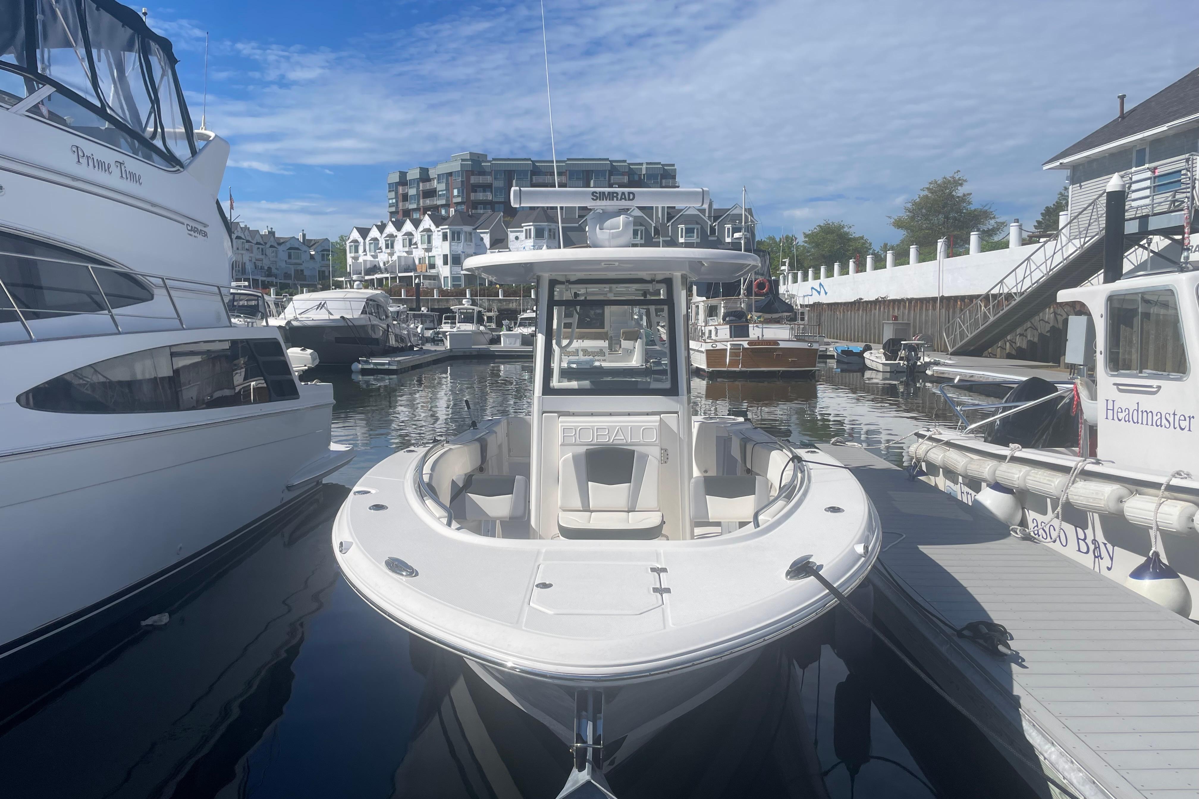 2023 Robalo R270 Center Console boat docked in a marina under a clear sky.