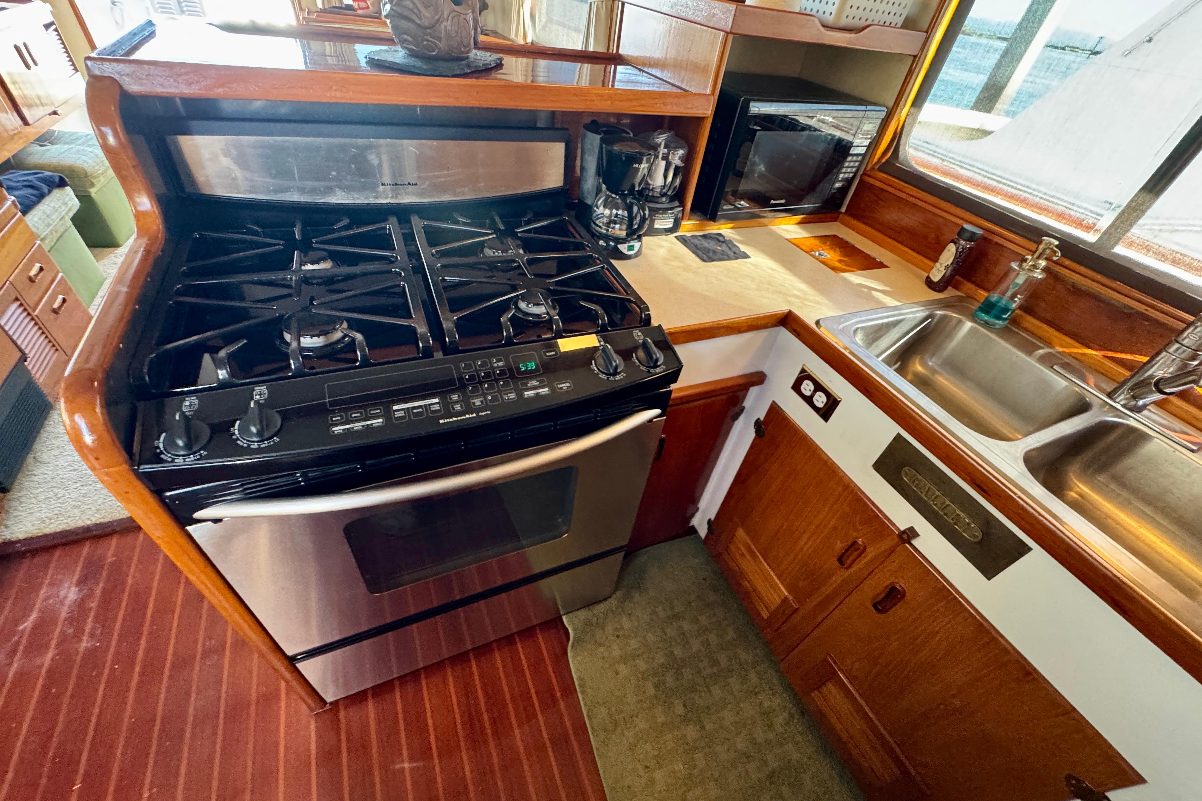 1958 Blanchard Pilothouse kitchen with stove, sink, and wooden cabinetry.