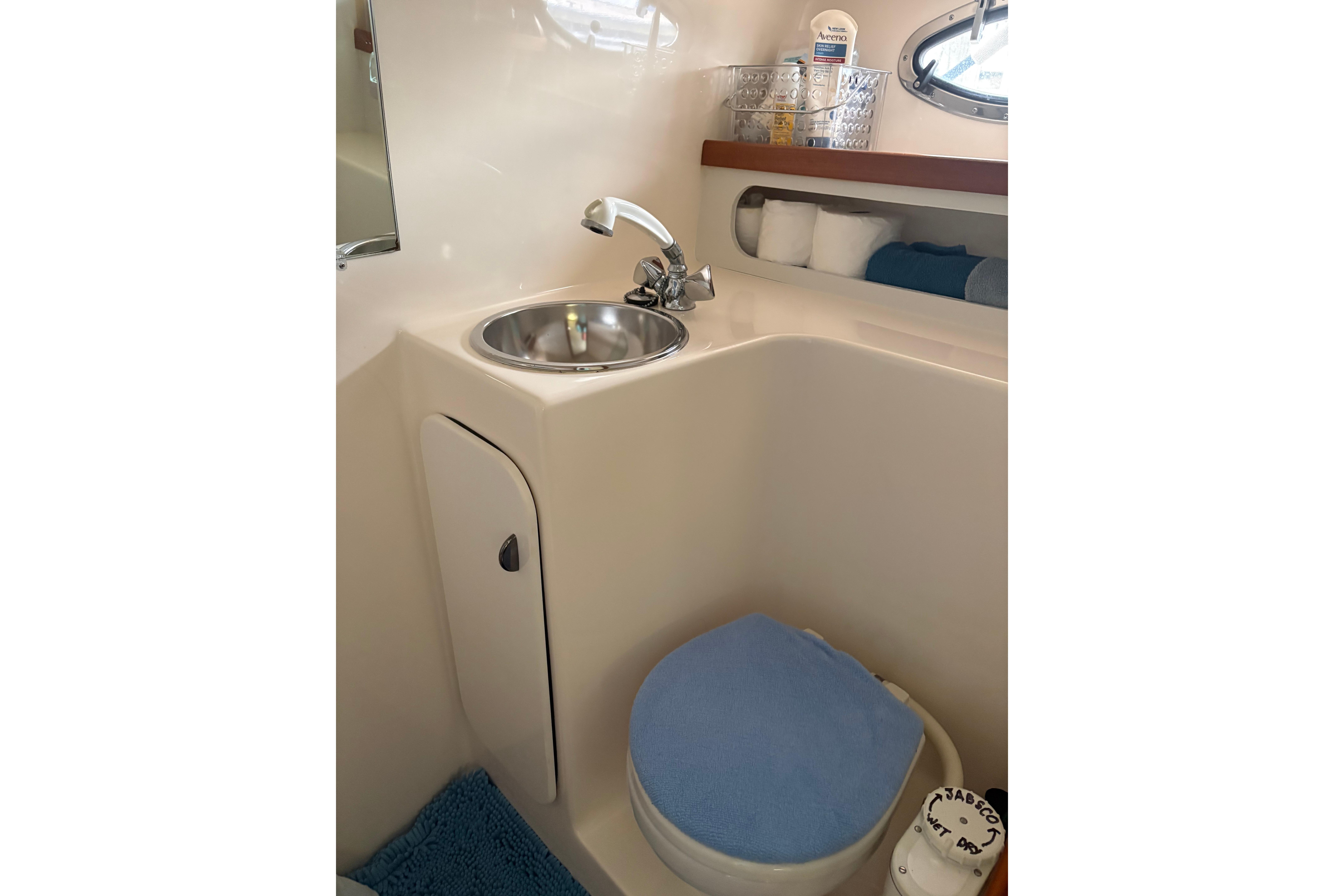 1999 Tiara Yachts 3100 Open bathroom with sink, toilet, and storage shelves.