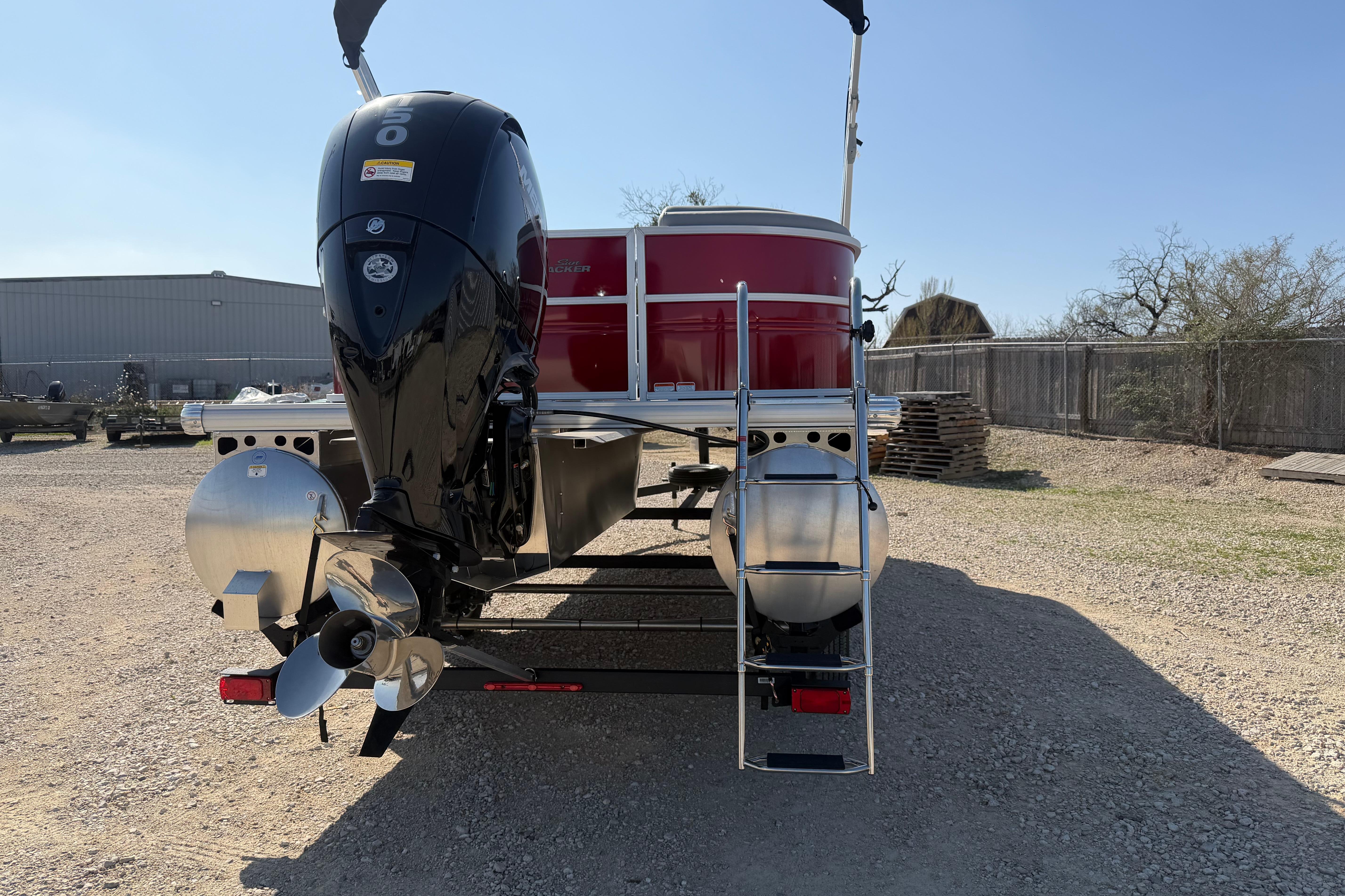 2026 Sun Tracker Party Barge 22 DLX pontoon boat with powerful outboard motor, rear view.