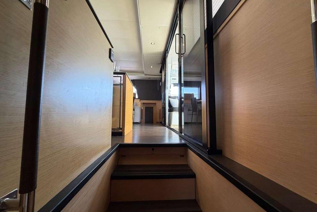Interior view of 2019 Lagoon 630 MY yacht, featuring modern wood paneling and glass doors.