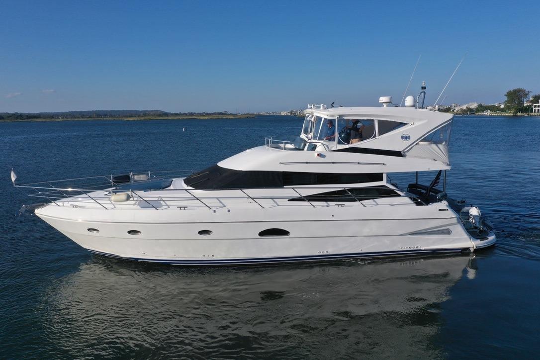 2005 Neptunus 56 Flybridge yacht cruising on calm waters under clear blue skies.