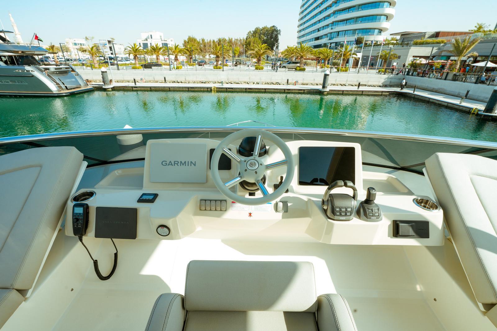 2024 Absolute NAVETTA 52 yacht helm with Garmin navigation, docked in a scenic marina.