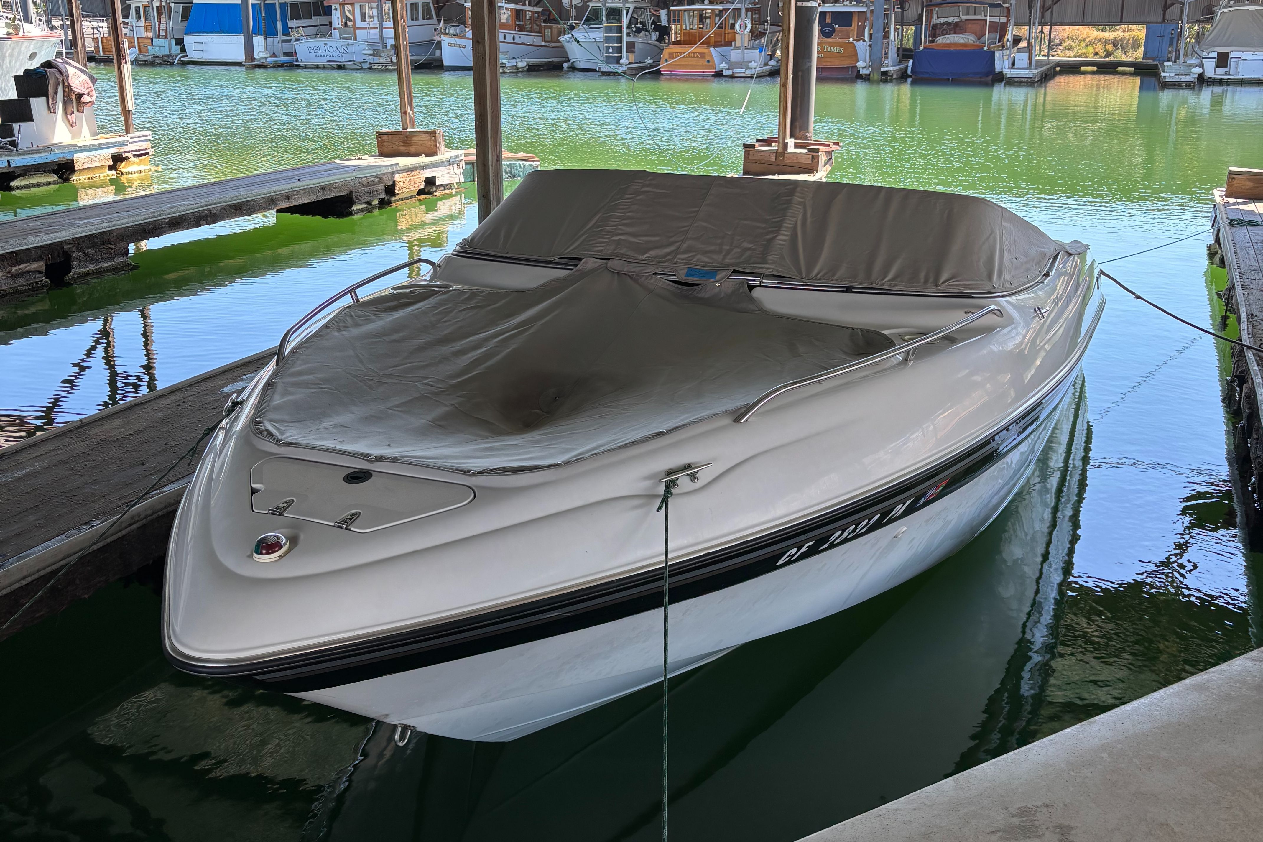 2000 Four Winns 220 Horizon in a marina, covered, on calm water.