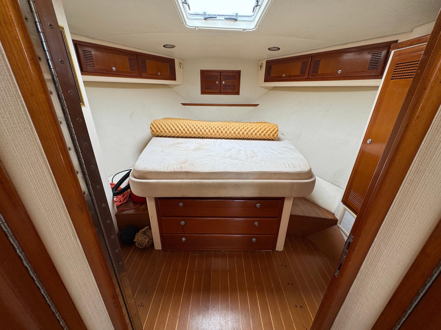 1999 Cabo 45 Express cabin interior with bed, wooden cabinets, and overhead hatch.