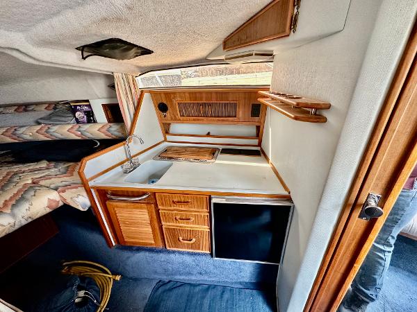 1987 Sea Ray 270 Sundancer cabin interior with kitchenette and cozy sleeping area.