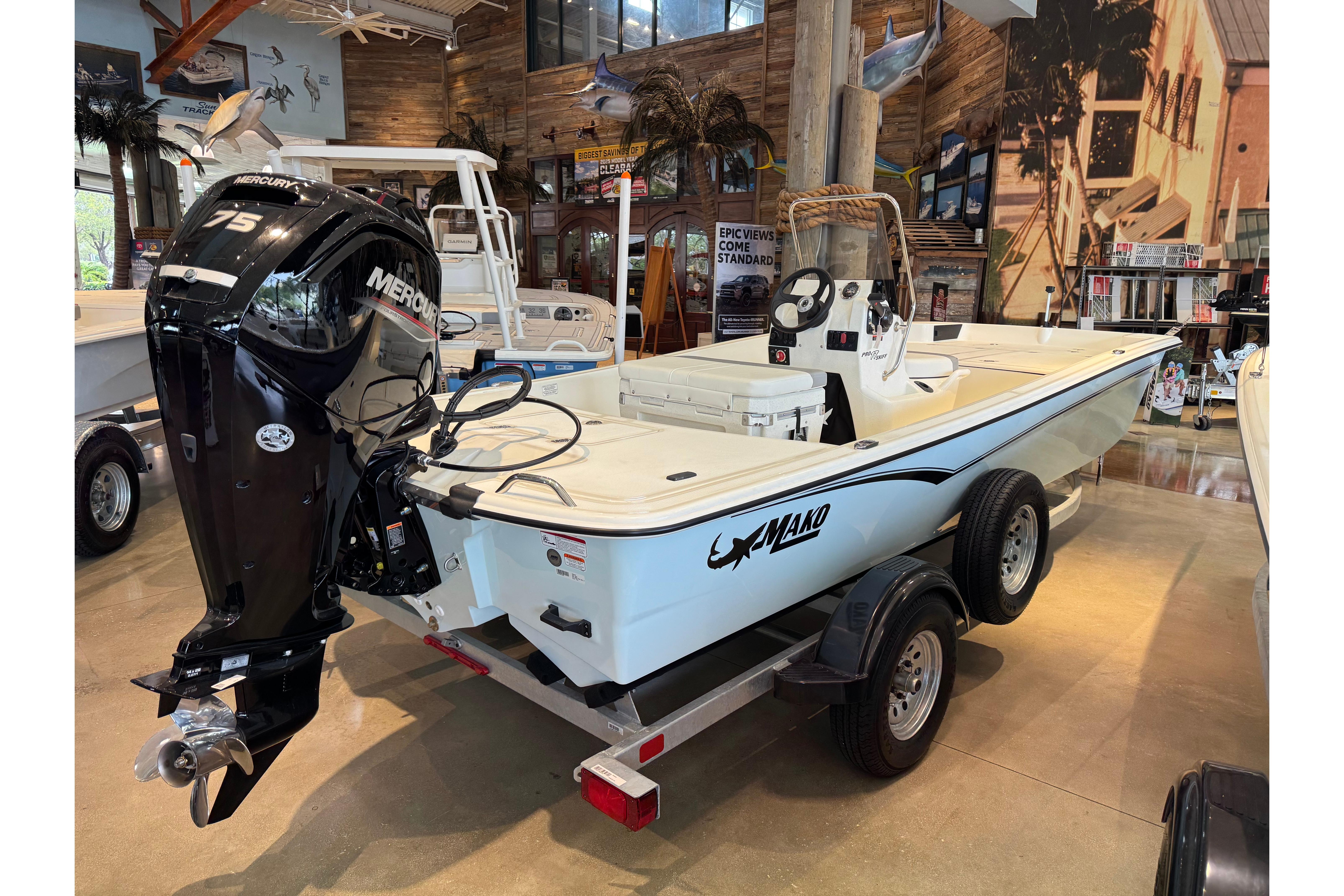 2026 Mako Pro Skiff 17 CC boat with Mercury 75 engine on display indoors.