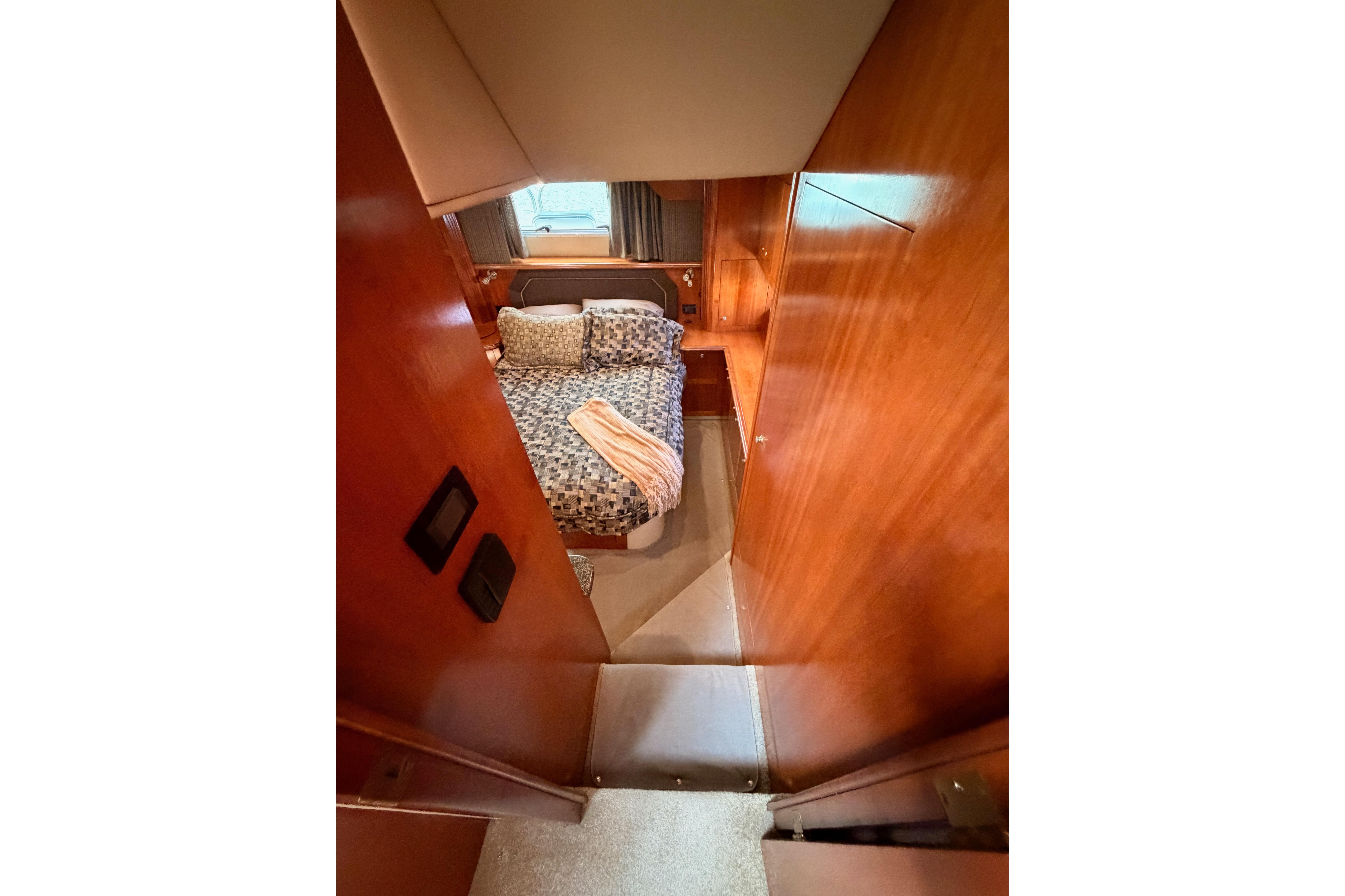 2005 Cruisers Yachts 405 Express Motoryacht cabin with cozy bed and wooden interior.