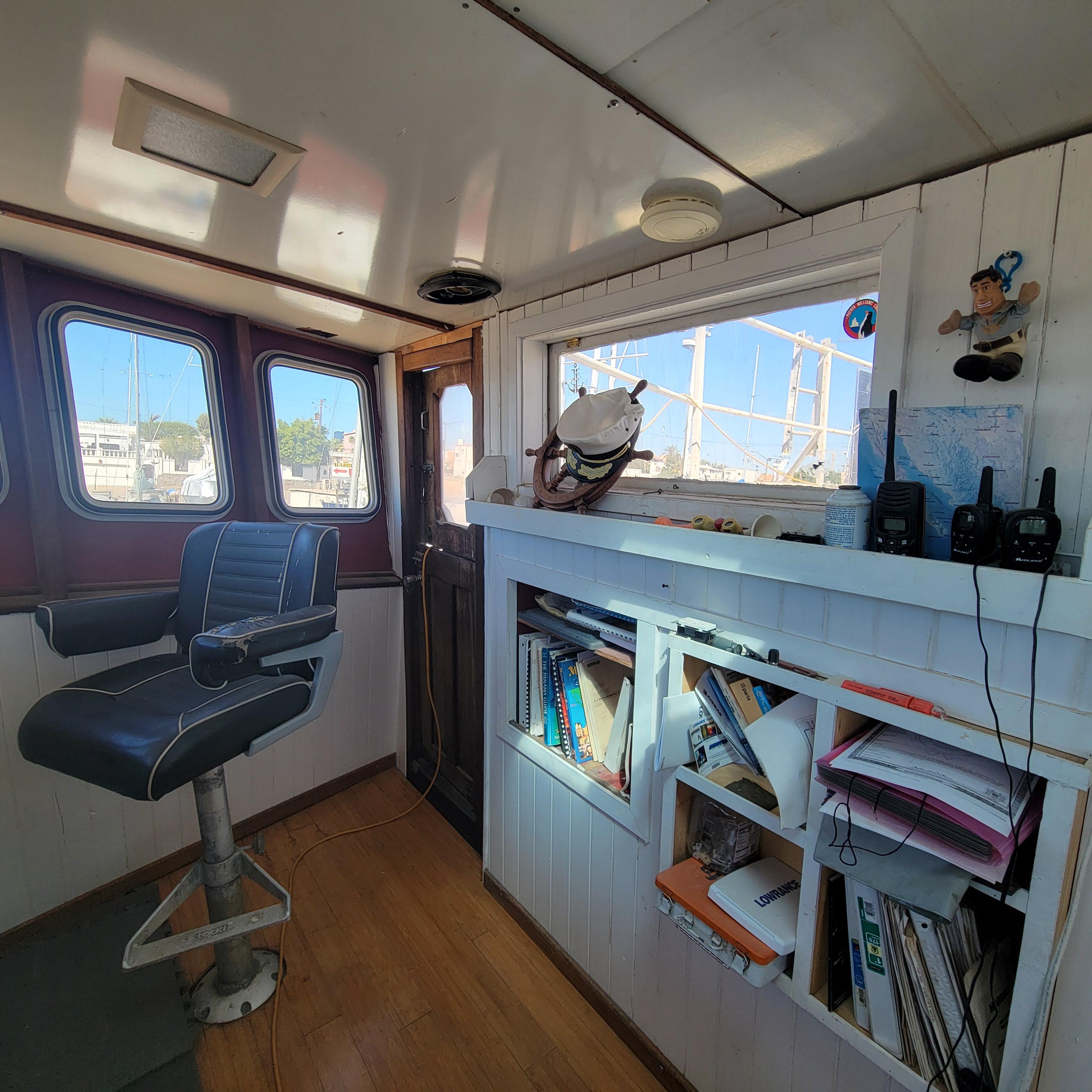 Interior of a 1979 Shrimper Conversion Trawler with chair, bookshelves, and nautical decor.