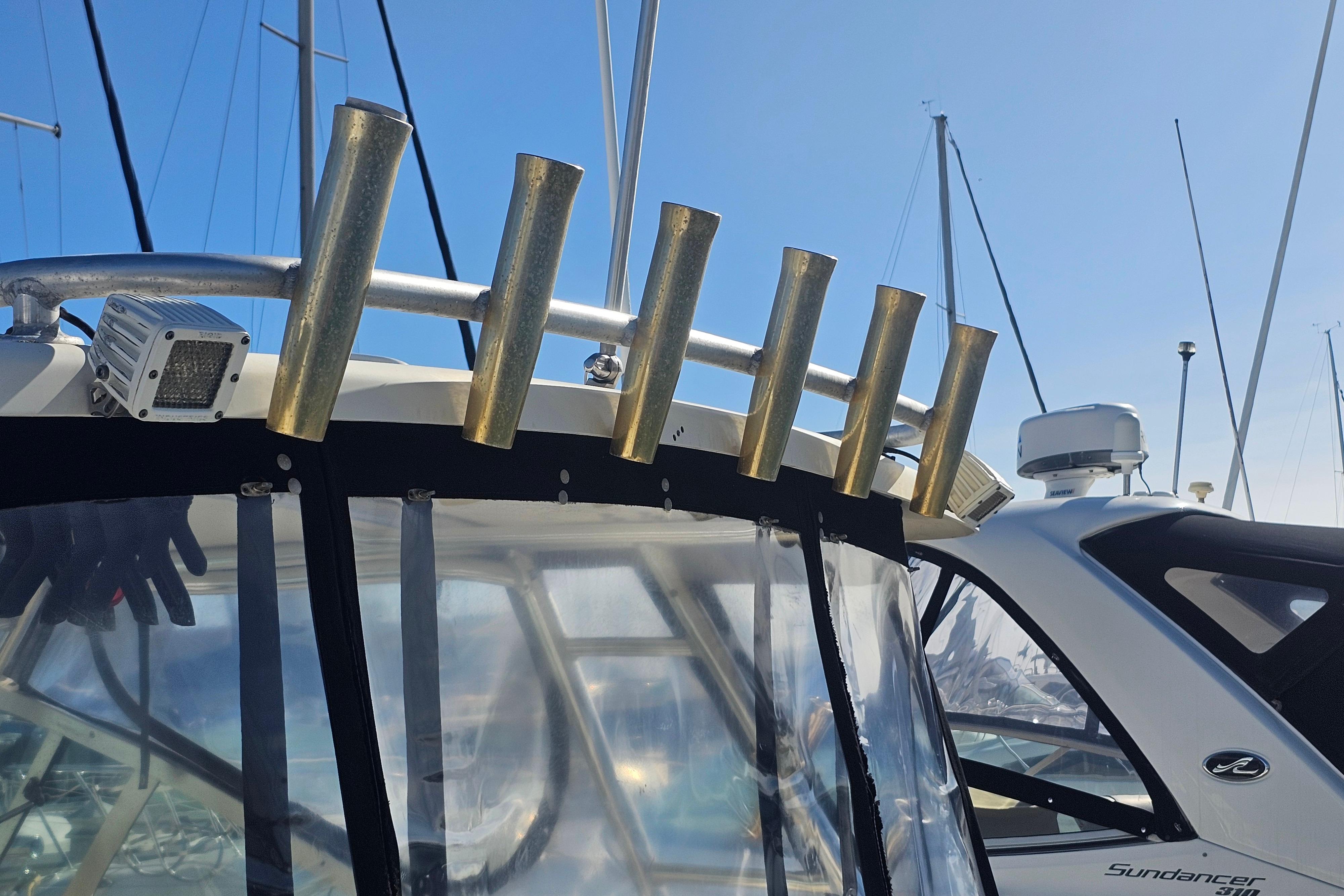2001 Pursuit 3000 Express boat with rod holders and radar, docked under clear blue sky.