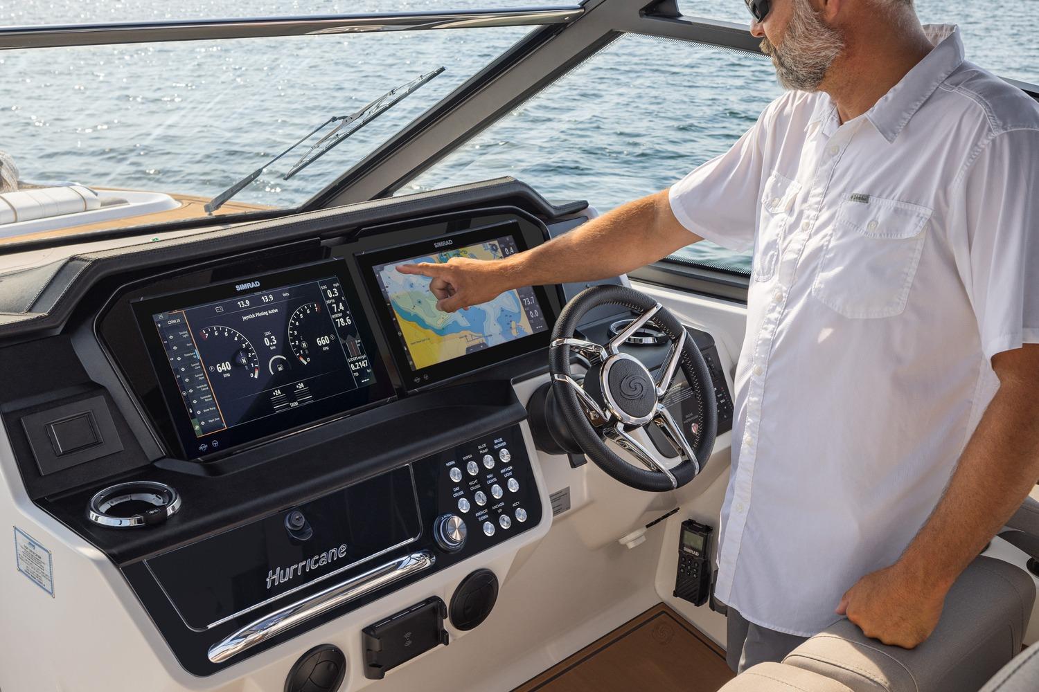 Man operating 2026 Hurricane SunDeck 3200 OB boat dashboard with navigation screens.