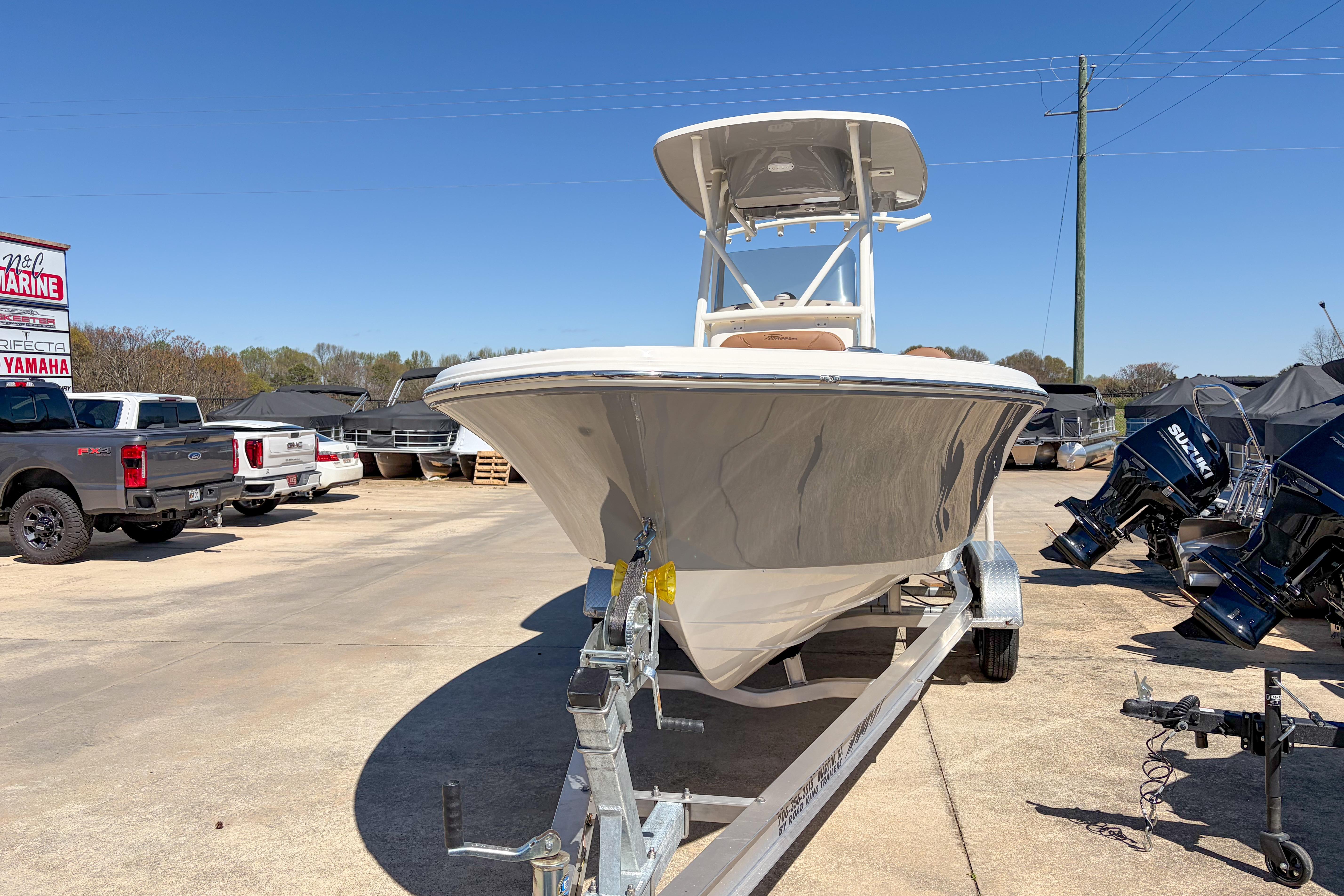 2026 Pioneer 220 Bay Sport boat on trailer at dealership, surrounded by trucks and outboard motors.