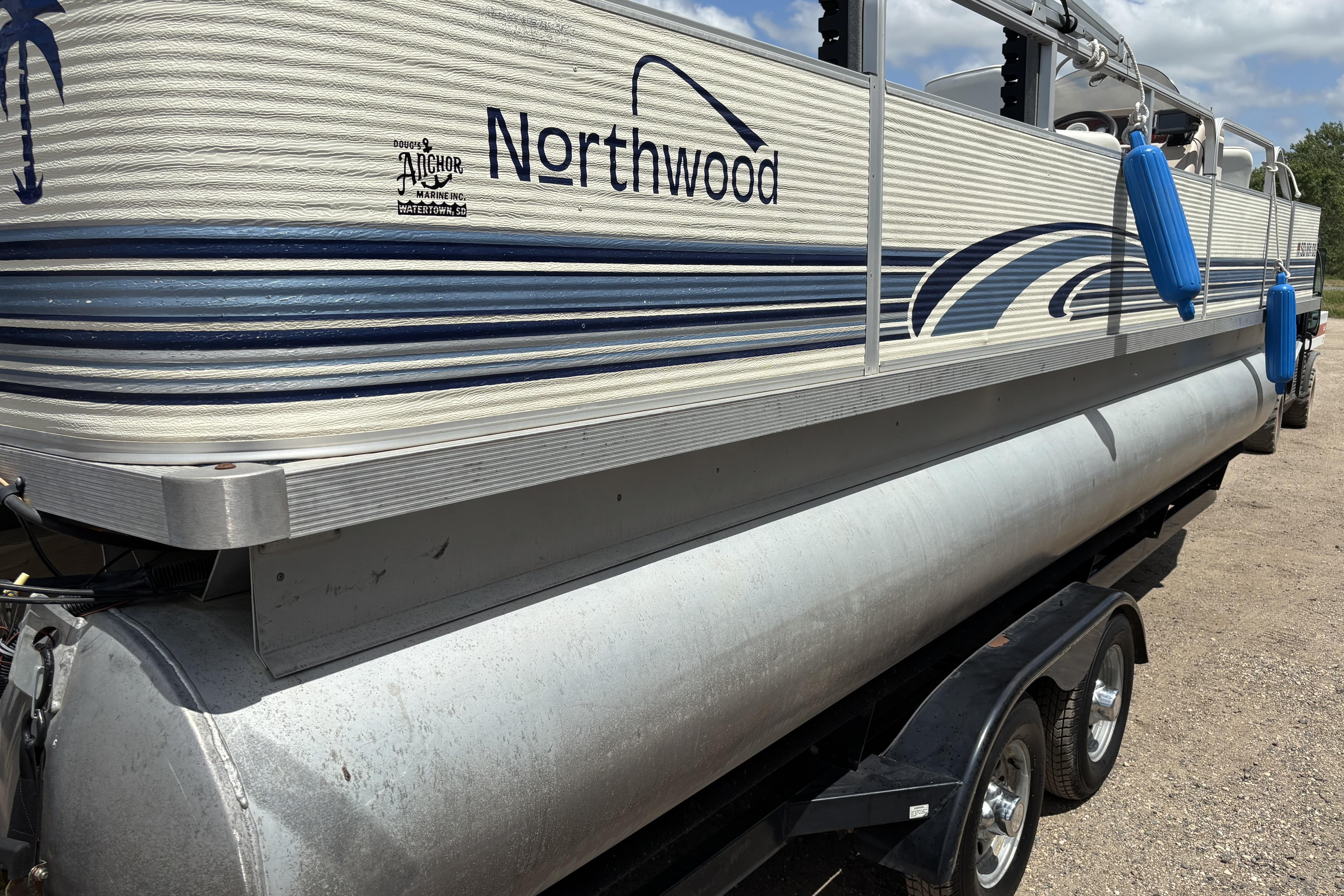 1997 Northwood 24' Pontoon boat on trailer, featuring blue accents and protective bumpers.