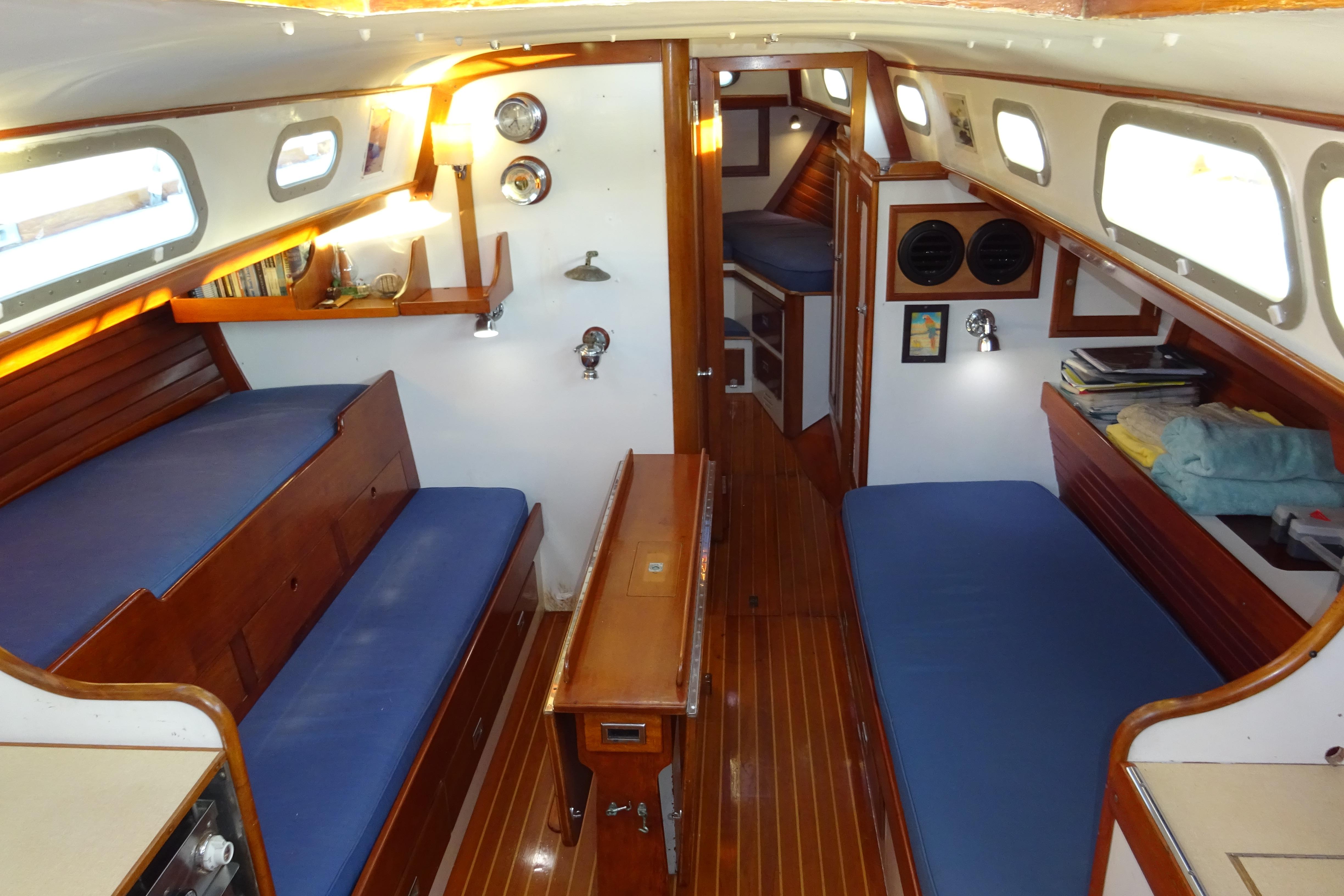 Interior of 1970 Hinckley Bermuda 40 Custom sailboat with wooden finishes and blue seating.