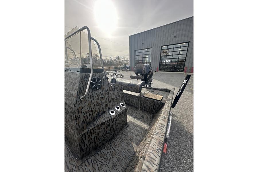 2026 Xpress H190B Bay boat with camouflage design, parked outside a warehouse.