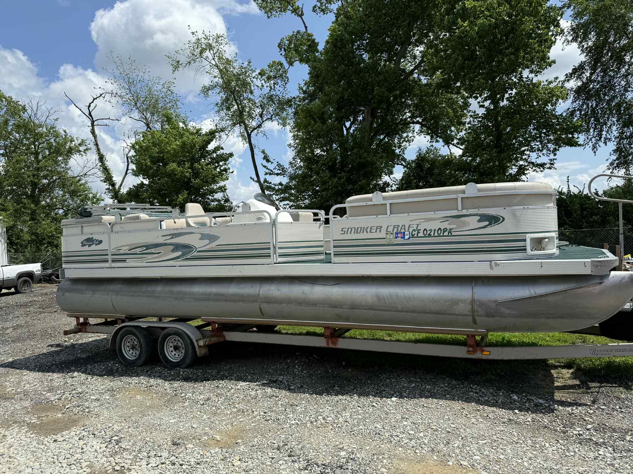 1999 Smoker Craft 8526 Pleasure Isle I/O pontoon boat on trailer, parked outdoors.