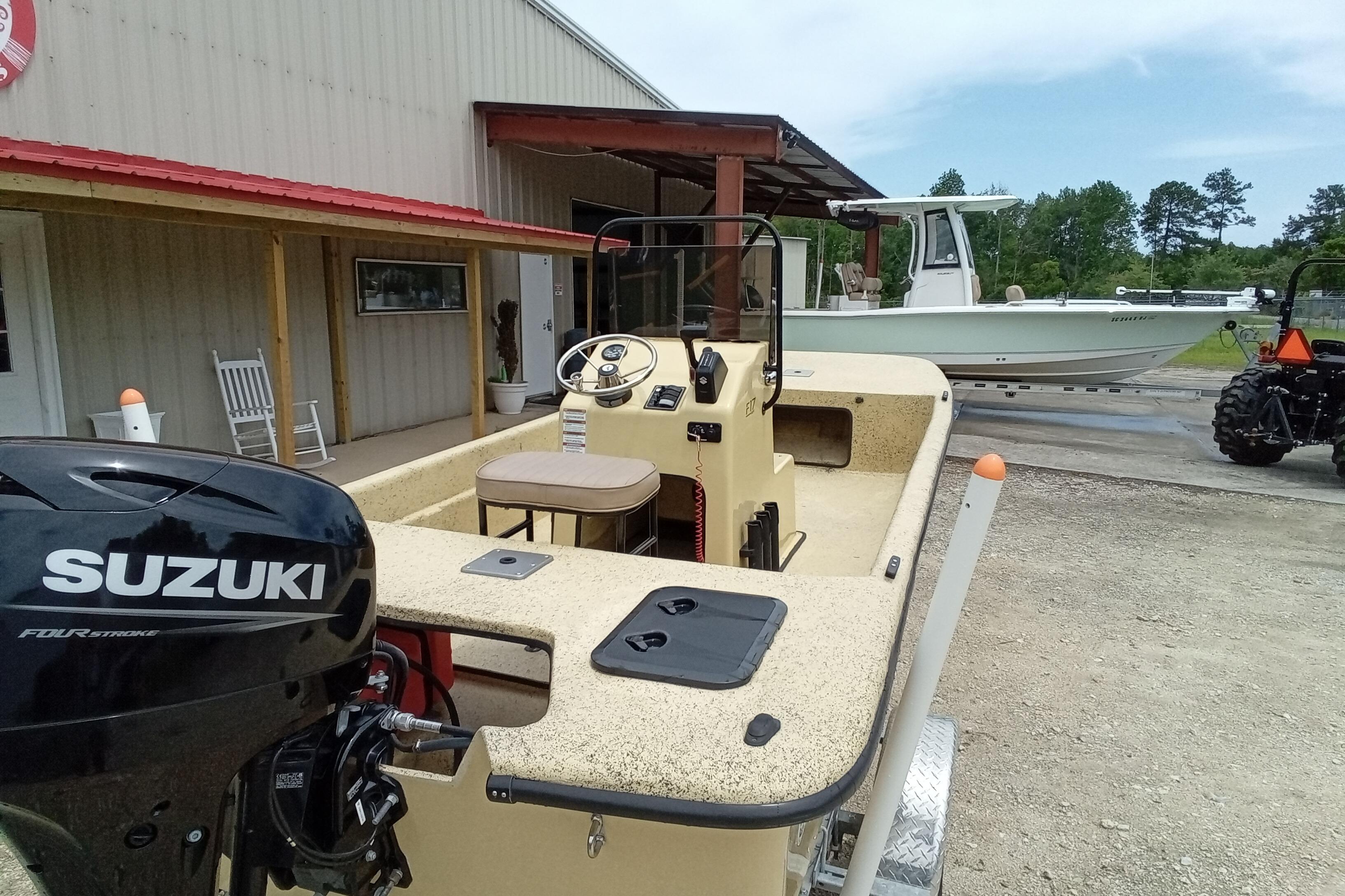 2025 Fibercraft F17 boat with Suzuki engine, parked near a building and tractor.