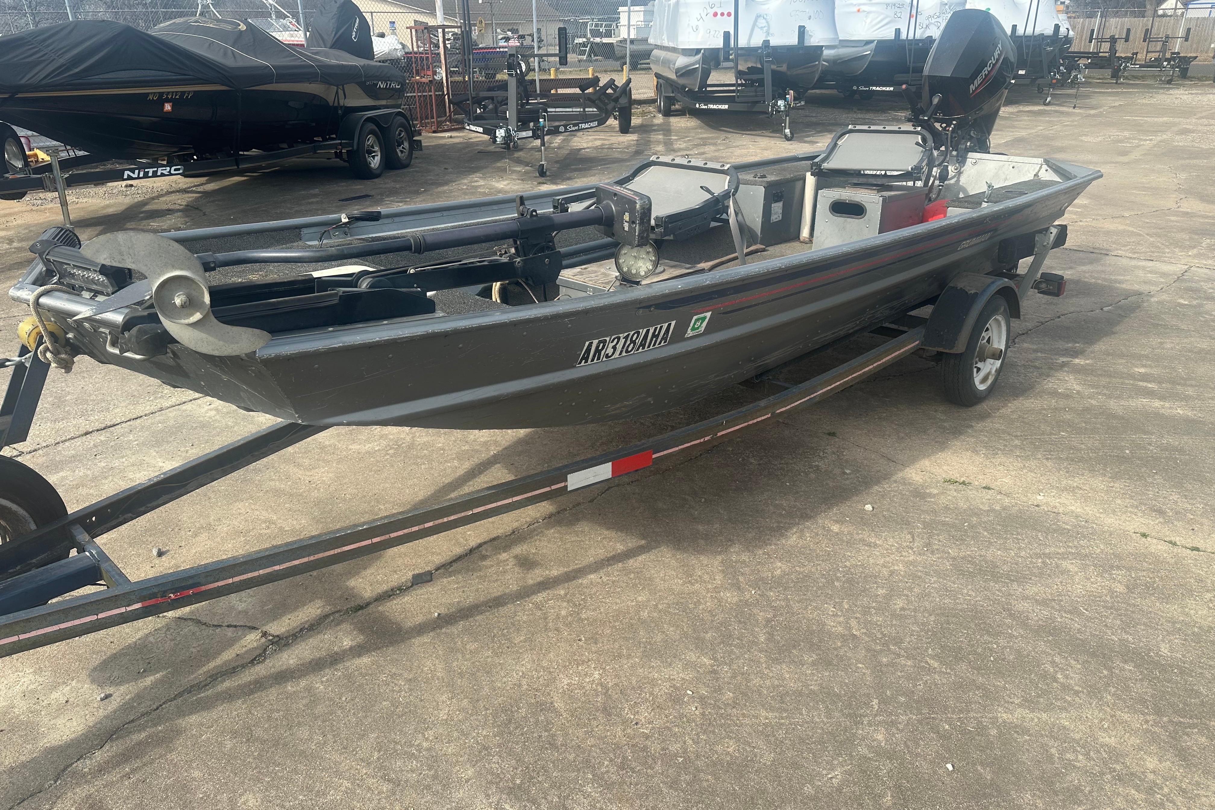 1991 Grumman Rogue 150 T boat on trailer, parked outdoors.