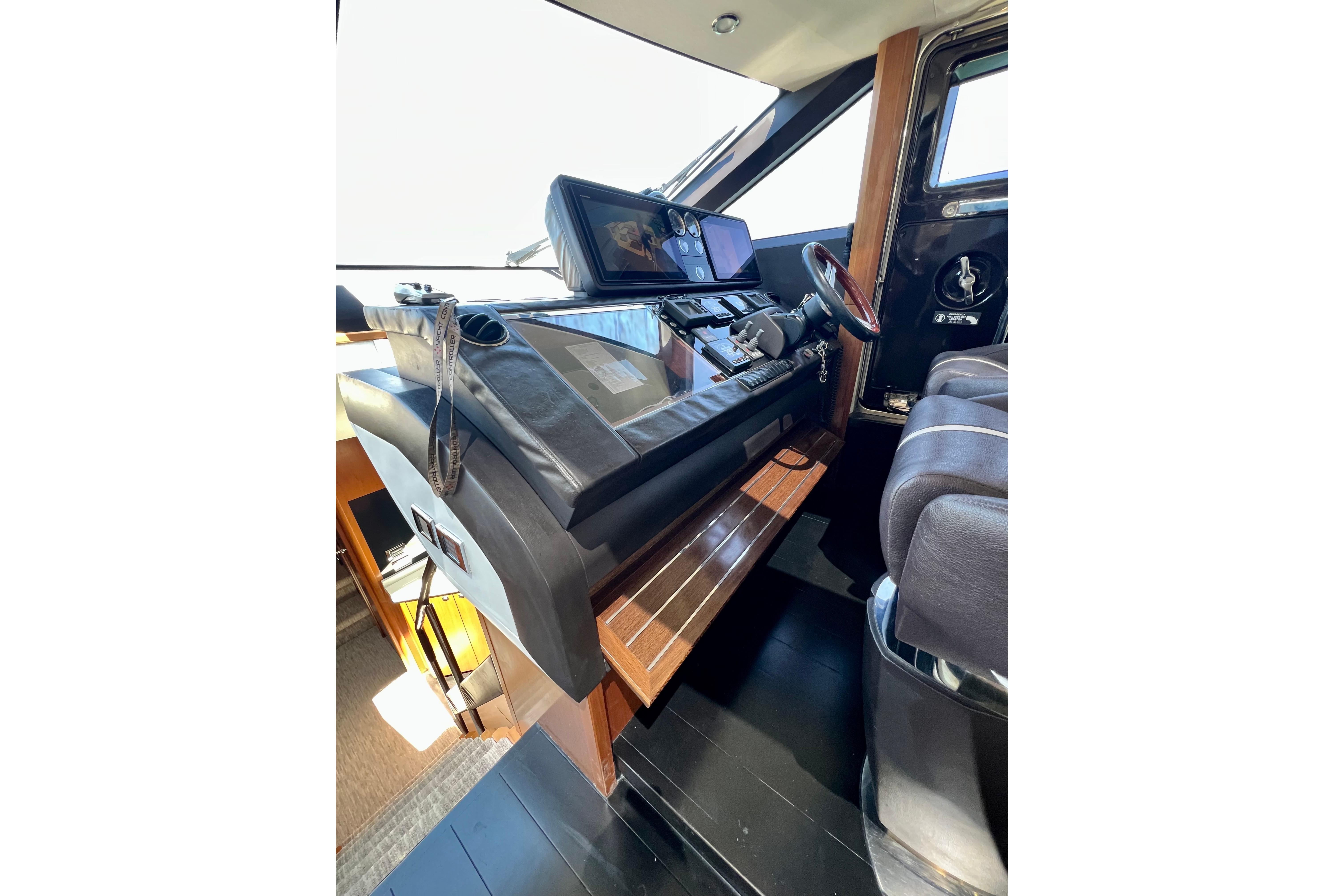 Interior helm of 2010 Princess V78 yacht with modern navigation equipment and leather seating.