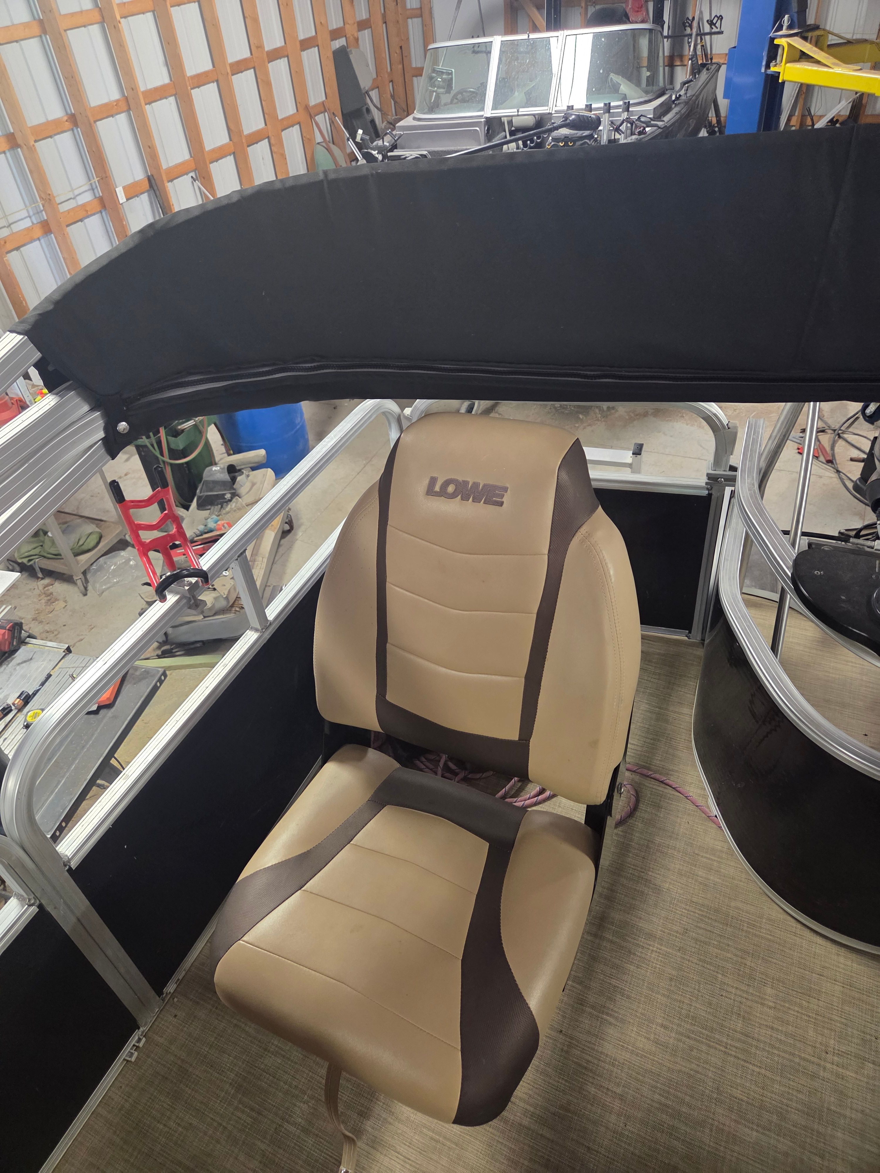 A boat seat labeled "Lowe" inside a workshop setting.