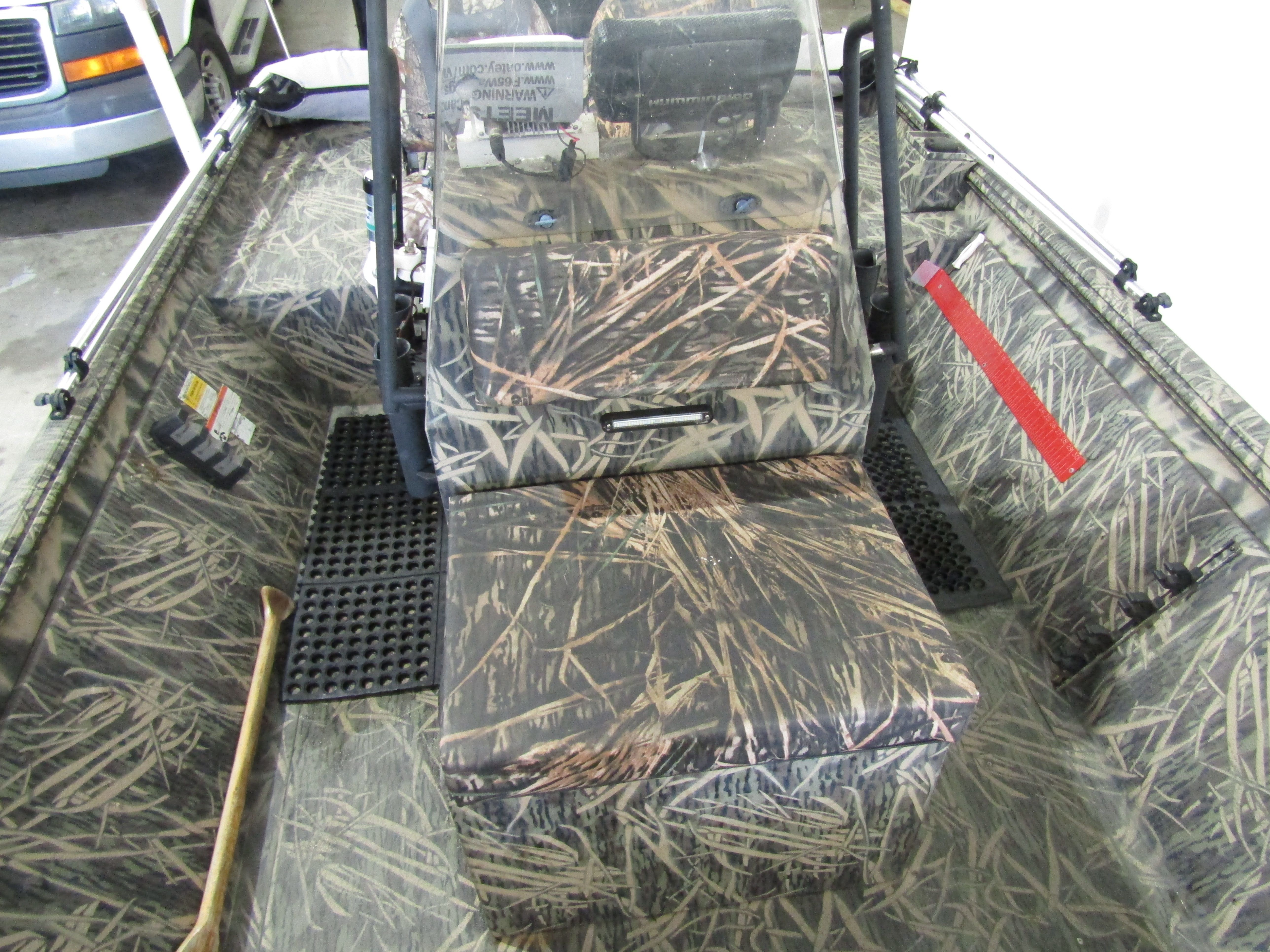 The image shows the interior of a boat with camouflage pattern and bench seating.
