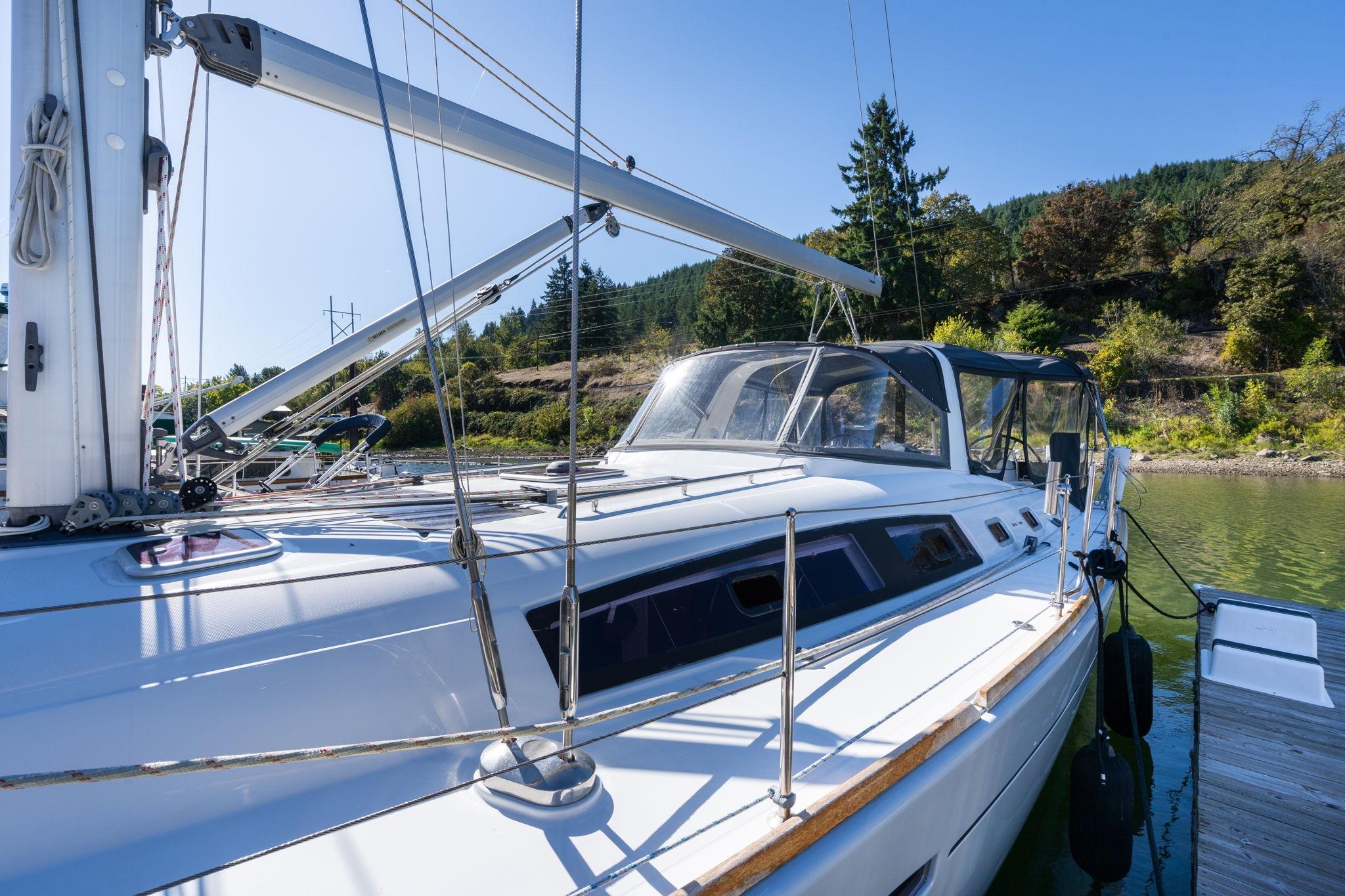 2013 Beneteau Oceanis 50 sailboat docked, surrounded by lush greenery and calm waters.