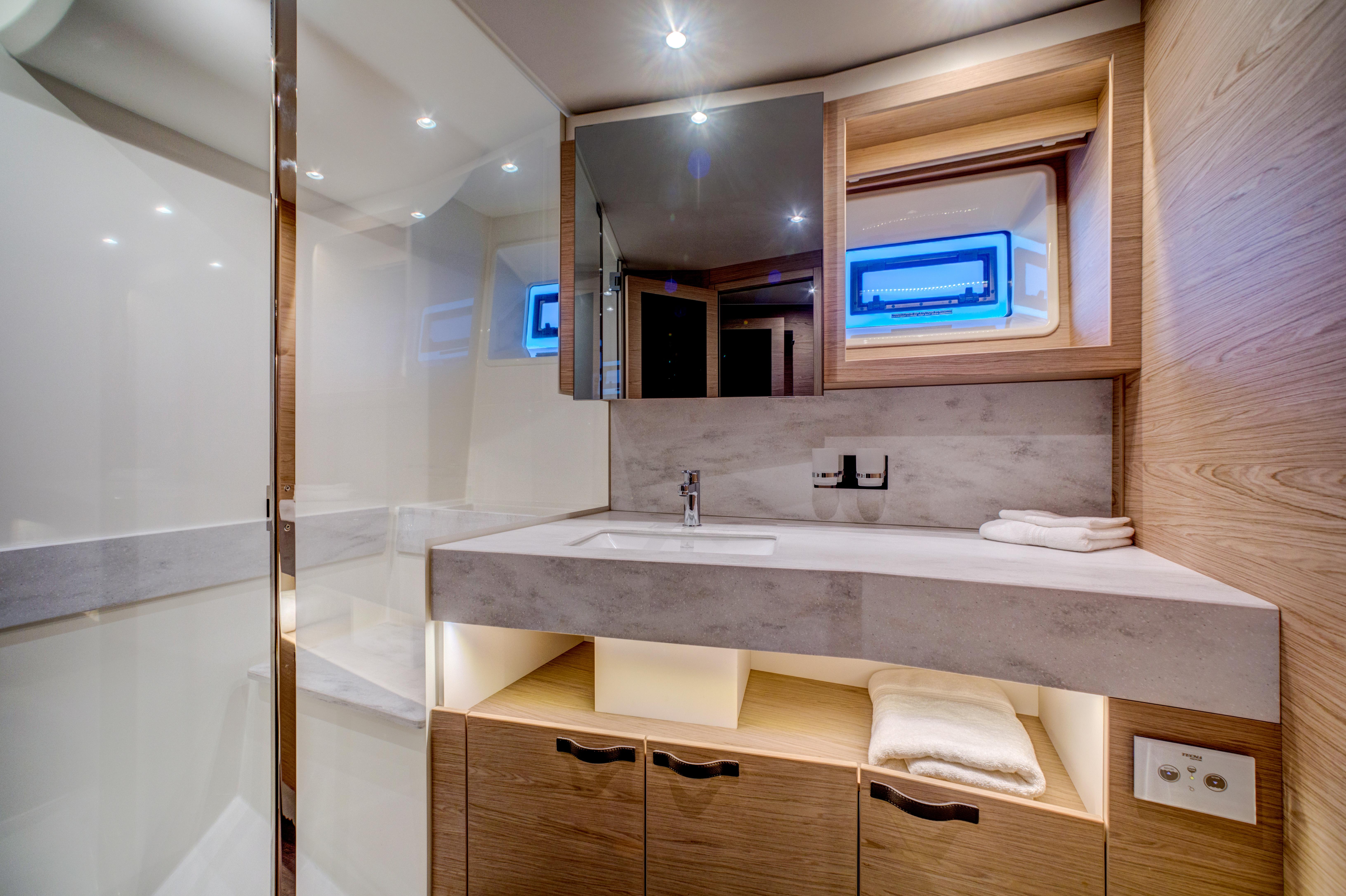 Luxurious bathroom in 2025 Beneteau Grand Trawler 62 yacht, featuring modern fixtures and wood accents.
