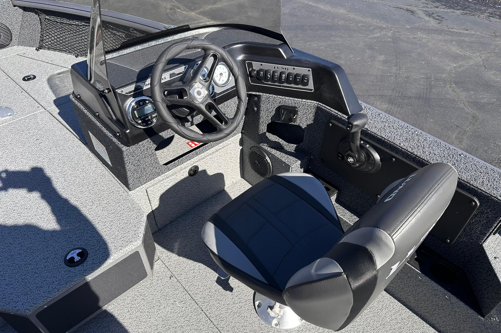 2026 Lund 1875 Impact XS SS boat cockpit with steering wheel and seat.